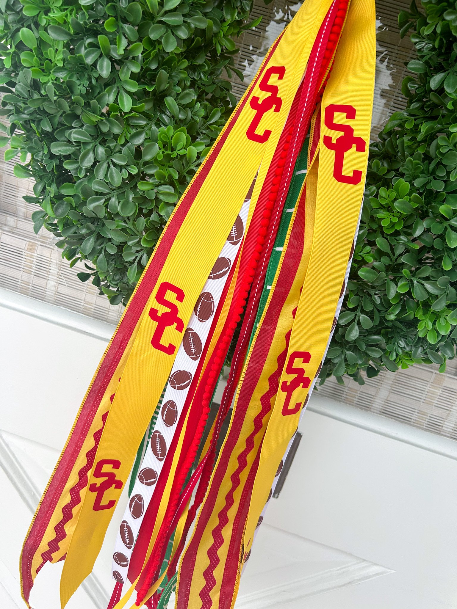 Multiple lanyards of yellow, red, green, and white colors with sports themes, including footballs and the logo of USC.