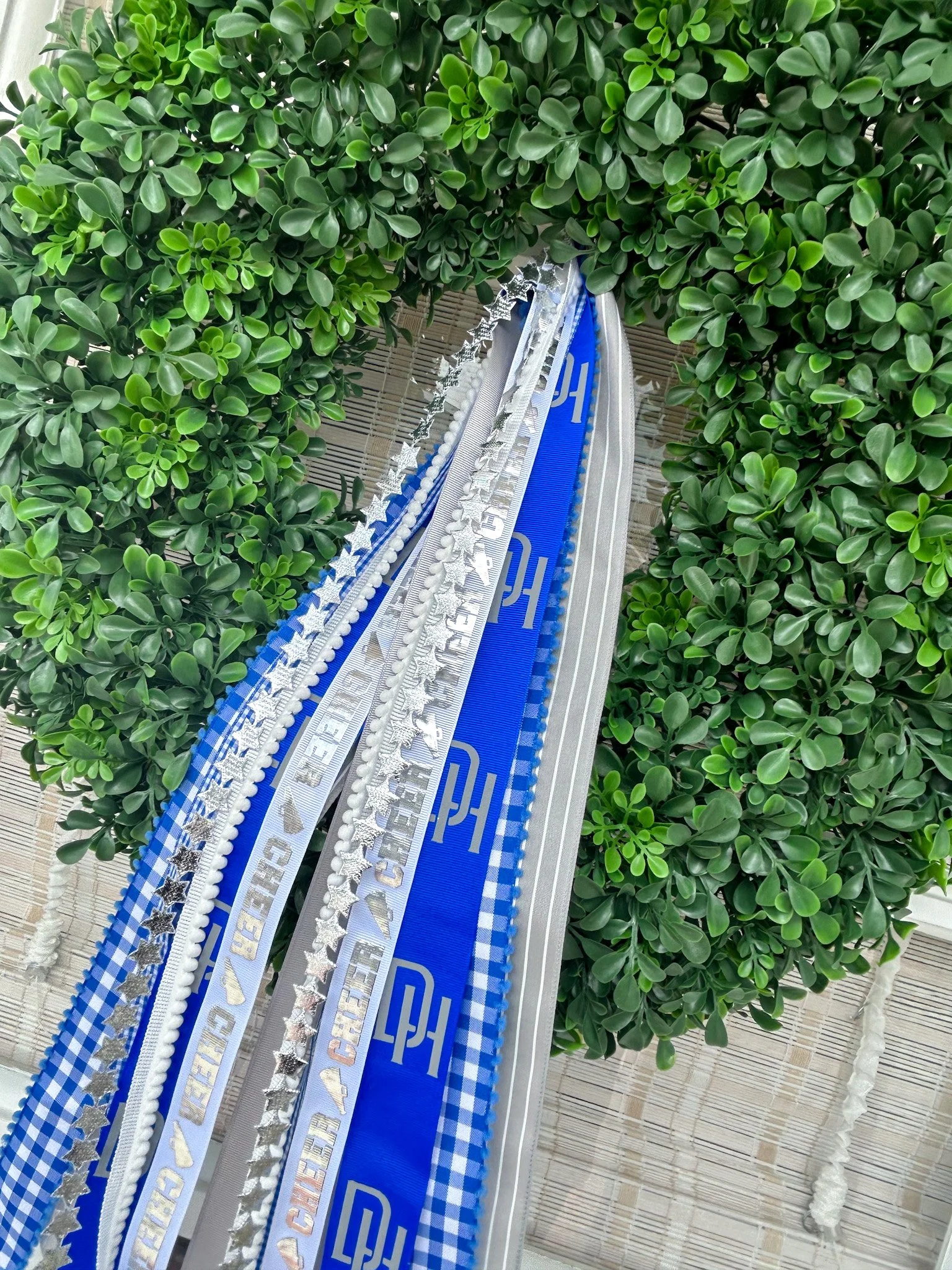 Decorative ribbons hanging from a boxwood wreath featuring cheer ribbon and dana point high school lettering.
