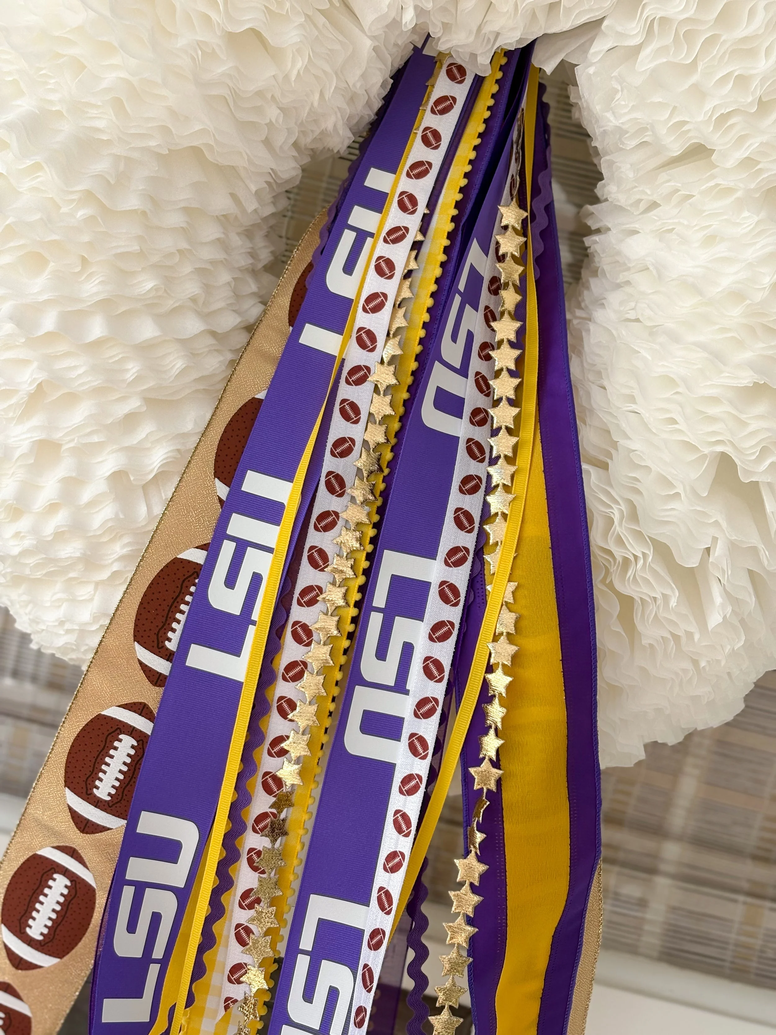 Decorative ribbons and garland with football motifs and gold star accents hanging against a white coffee filter wreath.