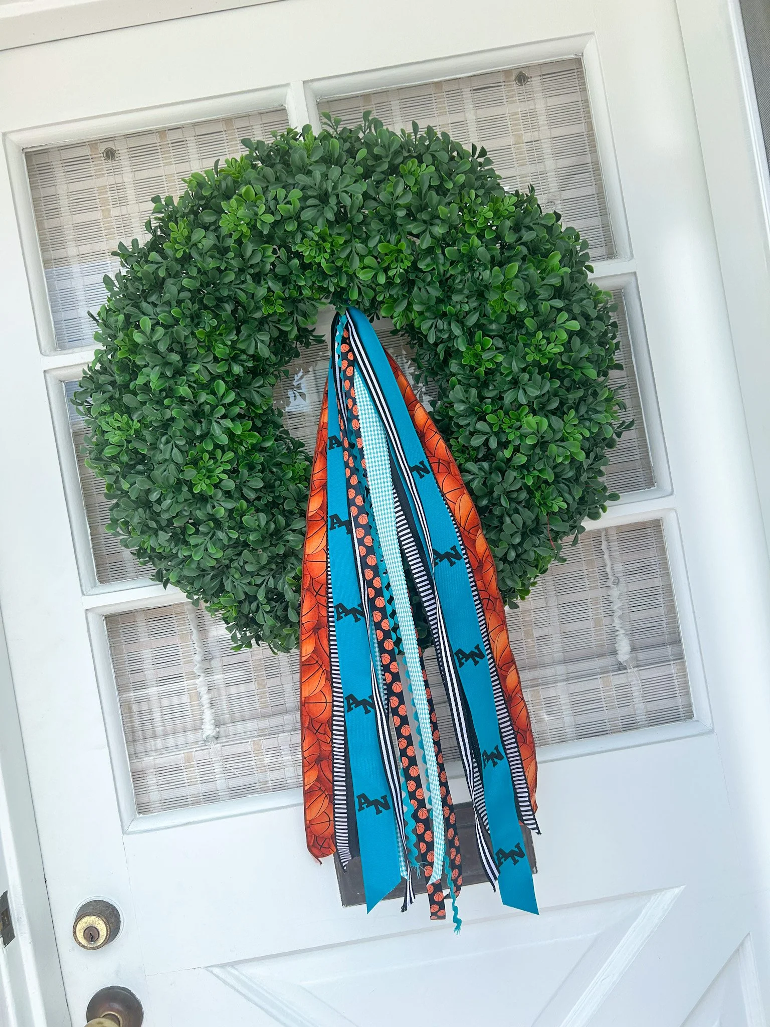 A green wreath with black, teal, orange, and white ribbons featuring Aliso Viejo High School and basketball motif.