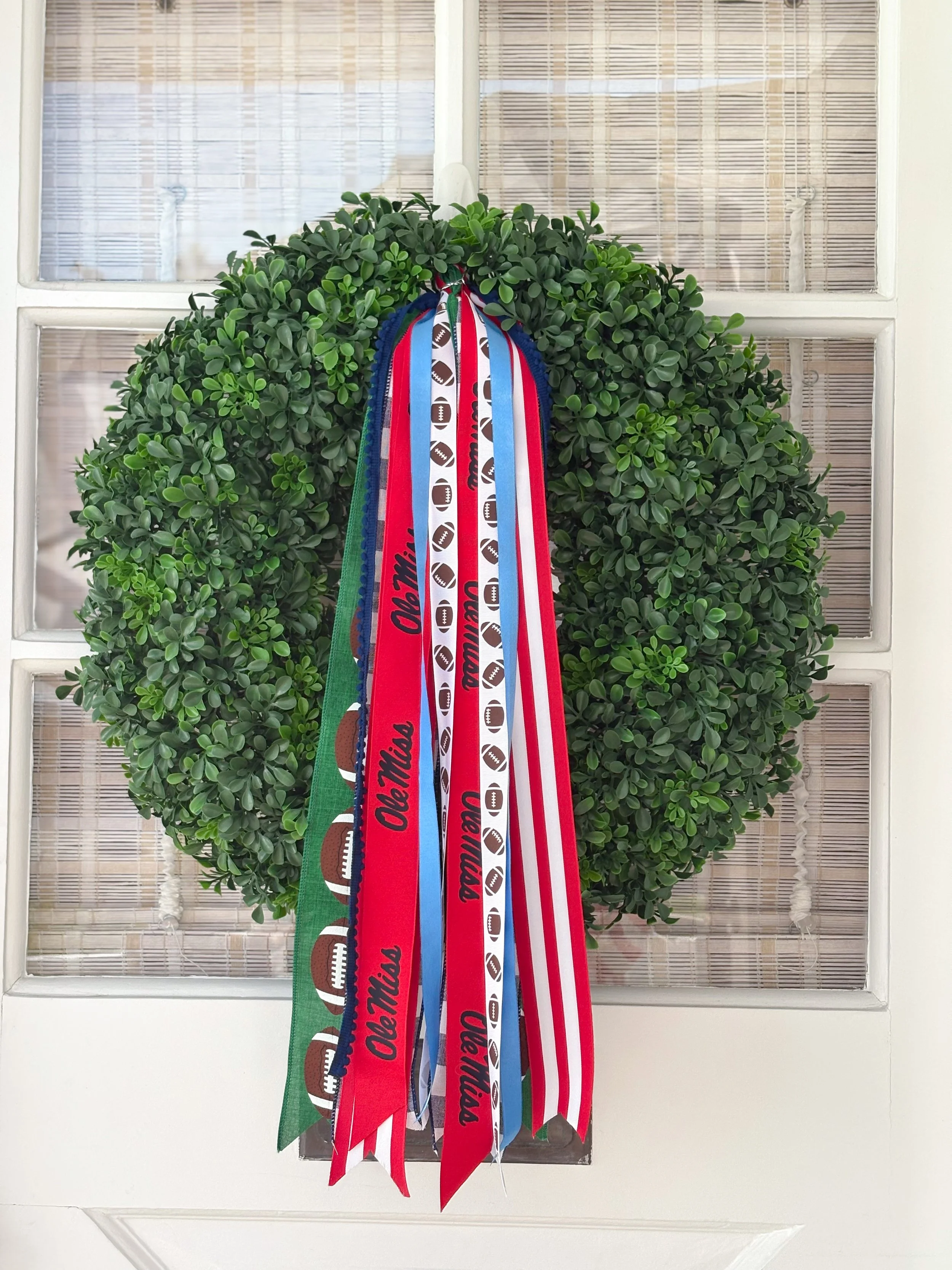 Green wreath decorated with dangling ribbons featuring Ole footballs and the words Miss.