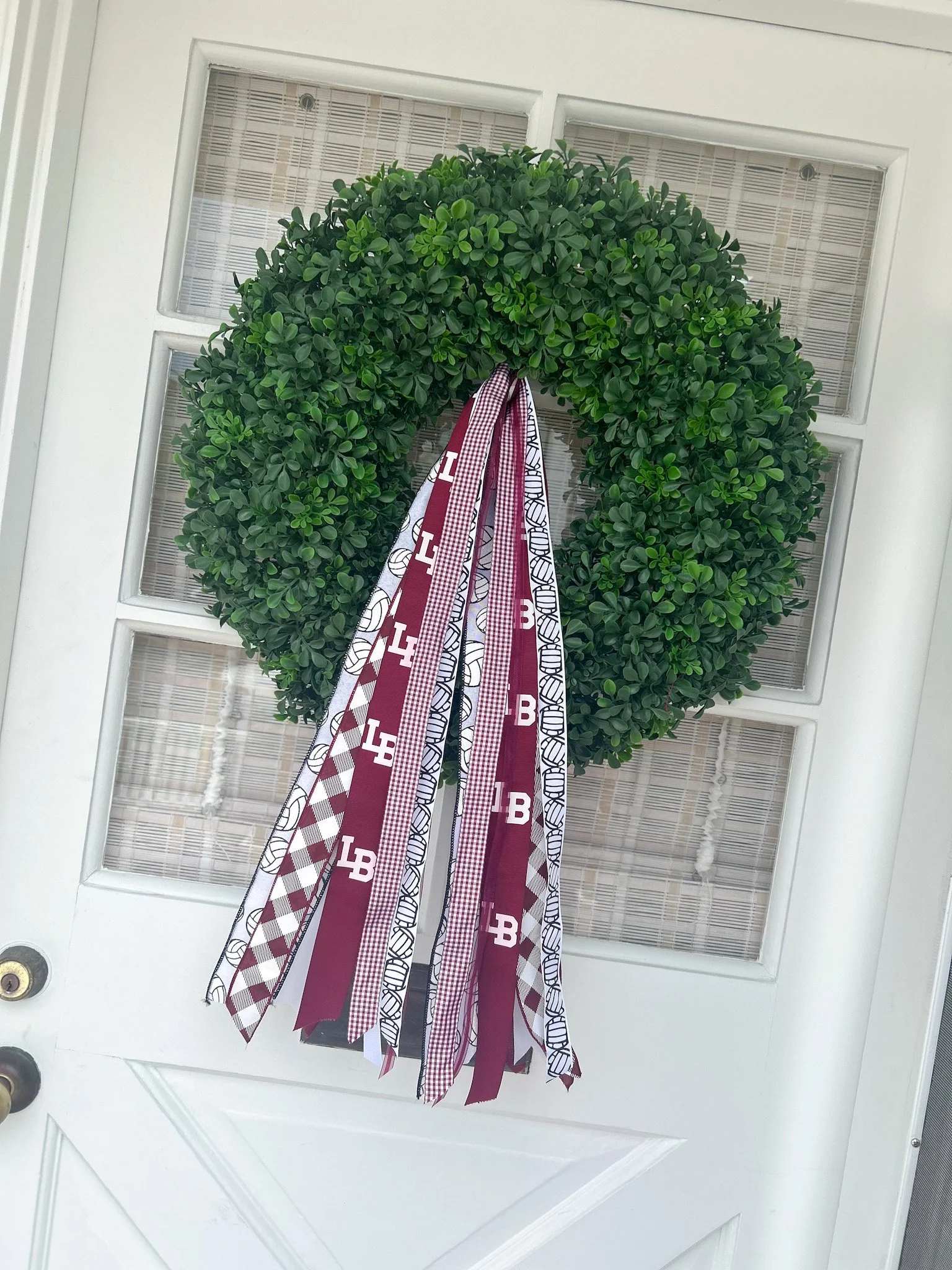 Decorative green wreath on a white door with rally ribbons hanging down.