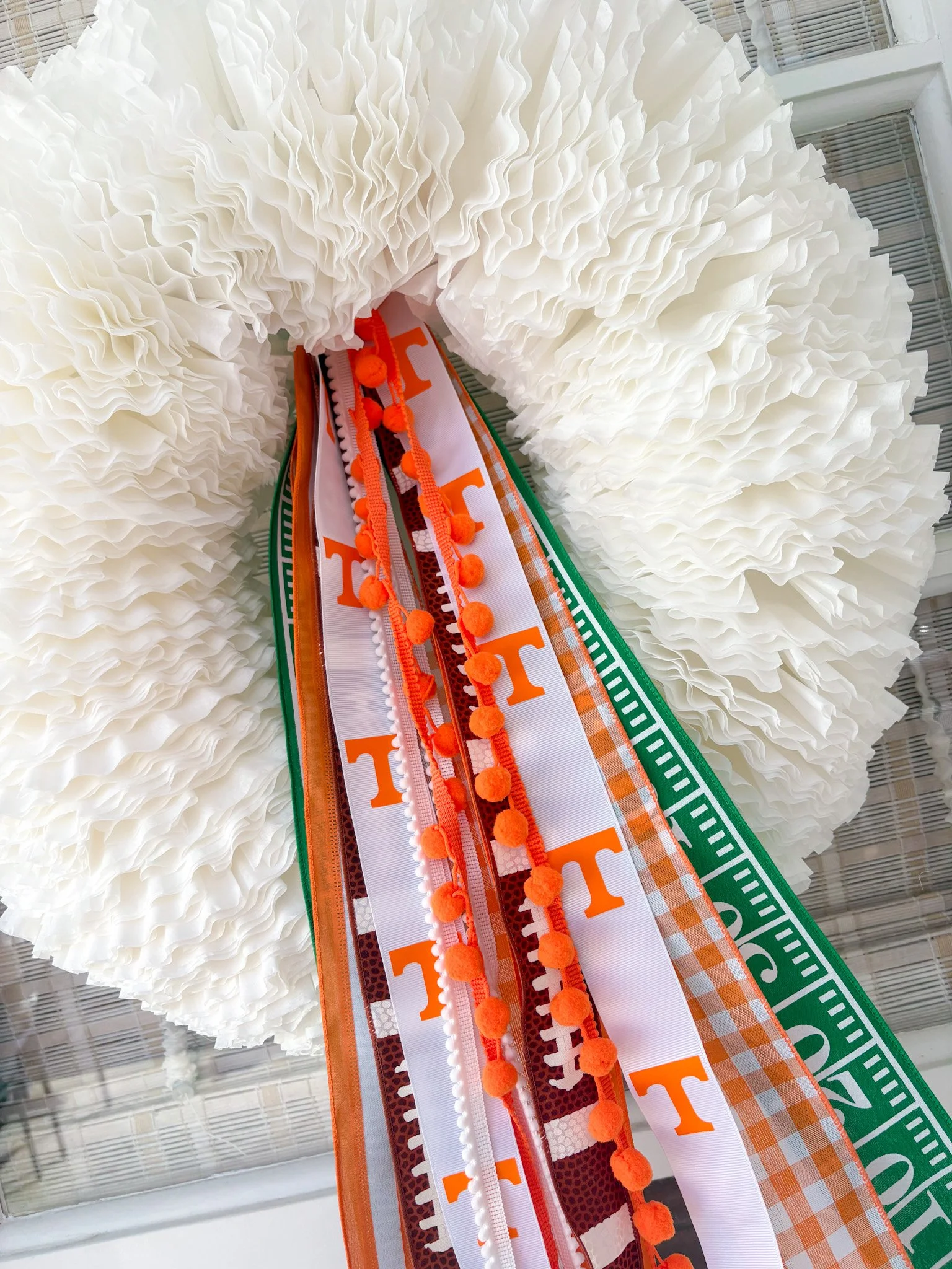 Close-up of a white fabric wreath with a Tennessee Volunteers-themed ribbon in orange and white at its center.
