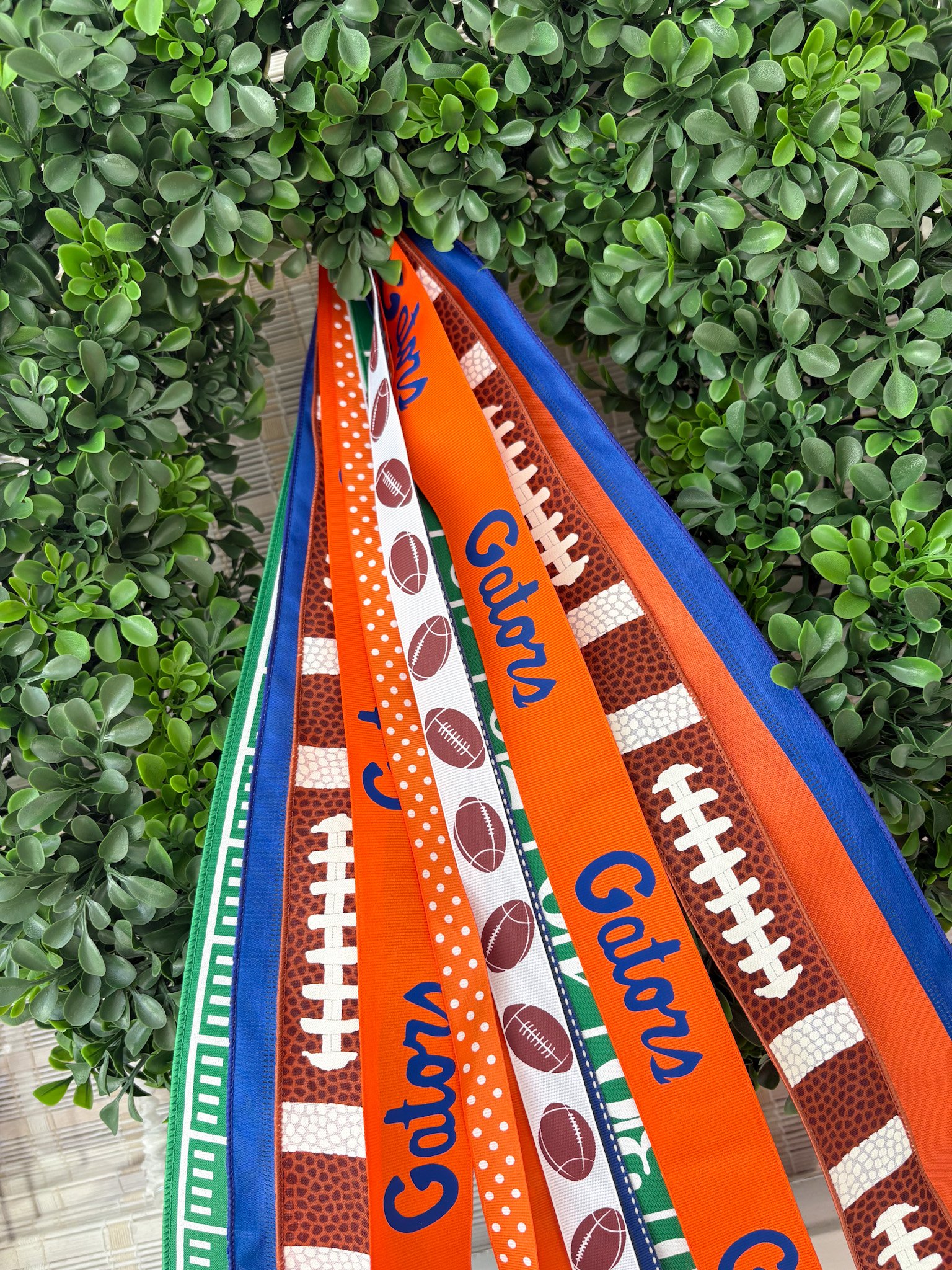 Green wreath with colorful ribbons featuring football patterns and the words 'Gators'.