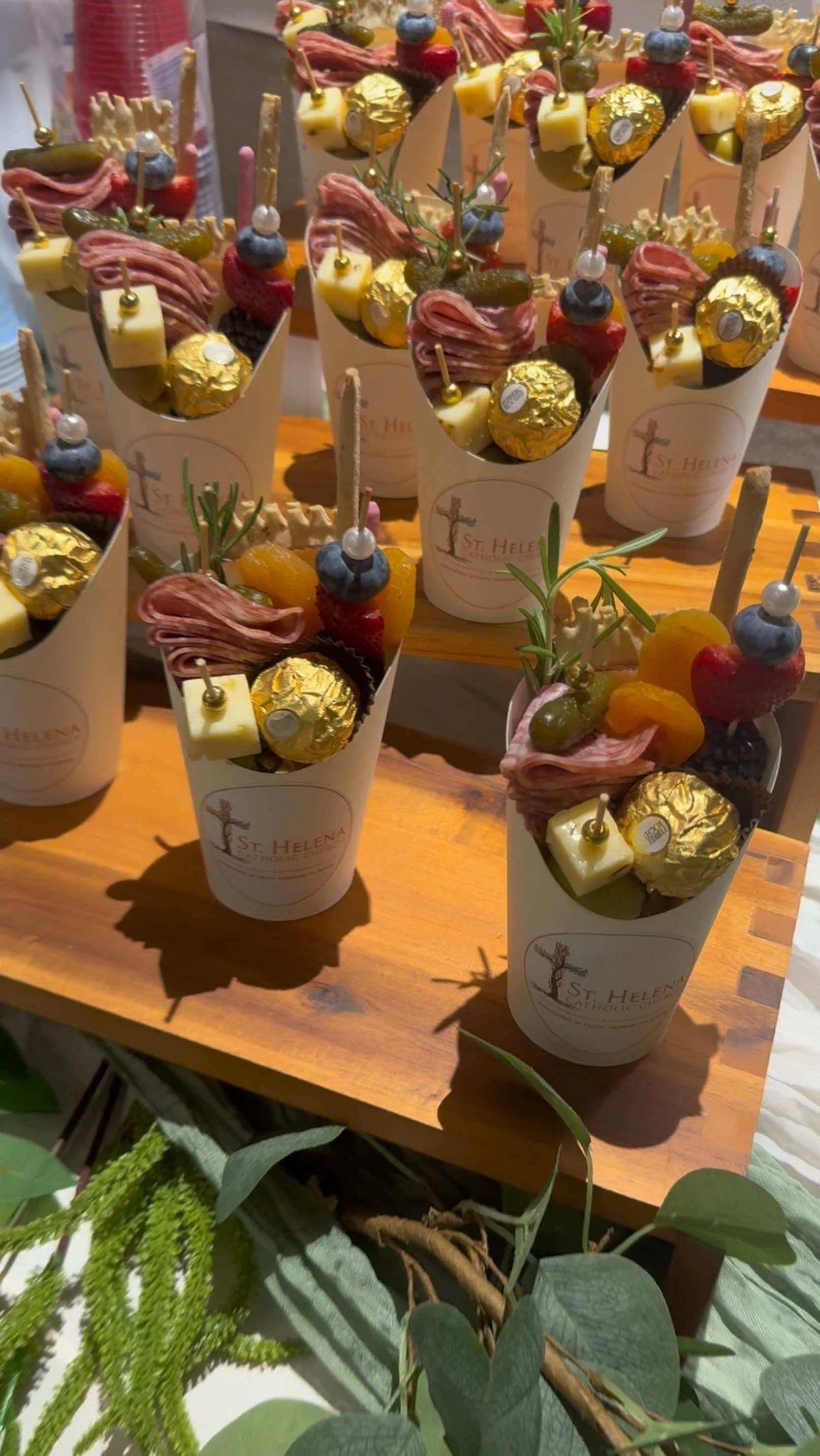 Custom charcuterie cups with cured meats, cheeses, fresh fruit, olives and sweet treats, personalized for a San Antonio church event.