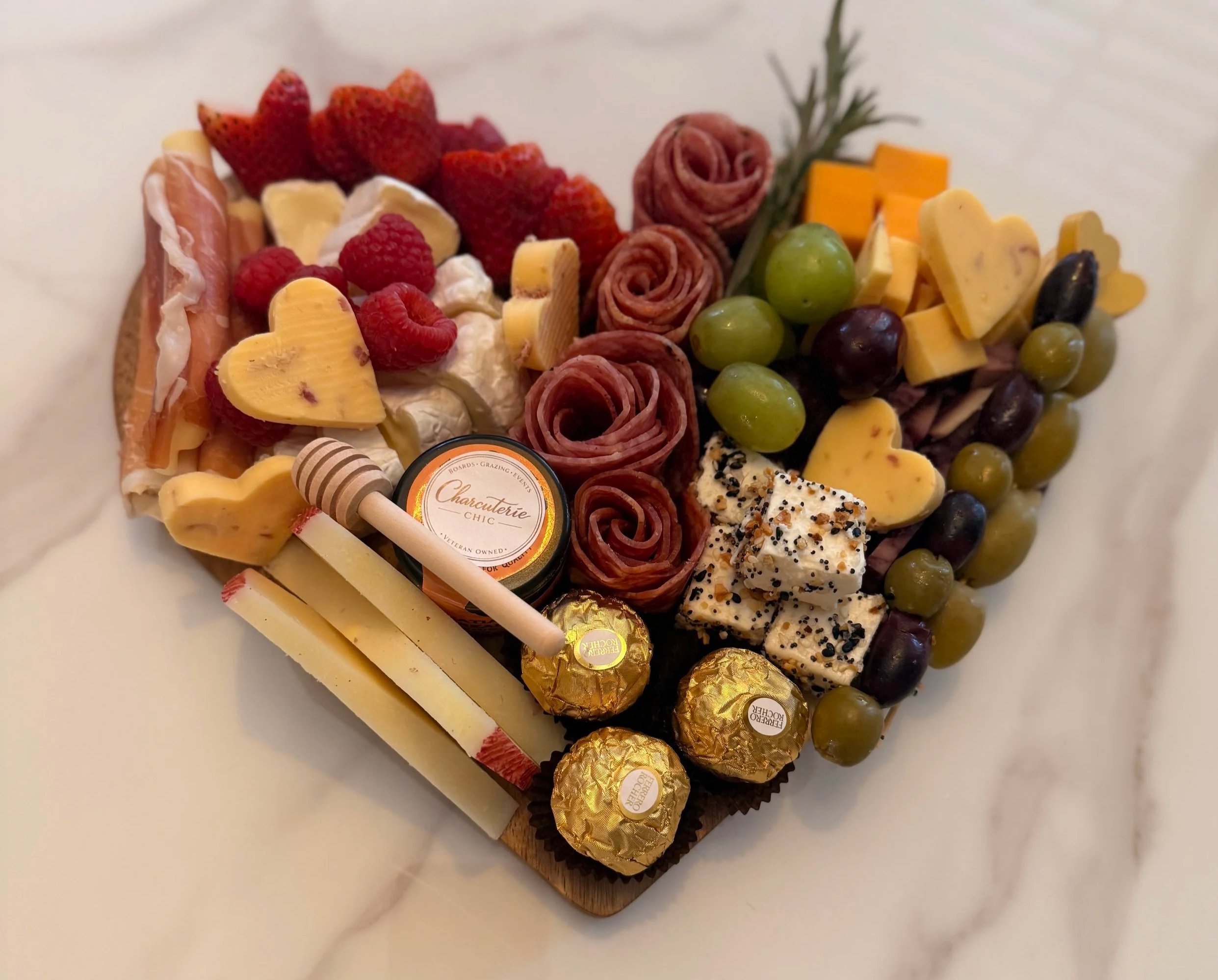 Small heart-shaped charcuterie board with meats, cheeses, grapes, and chocolates by Charcuterie Chic in San Antonio