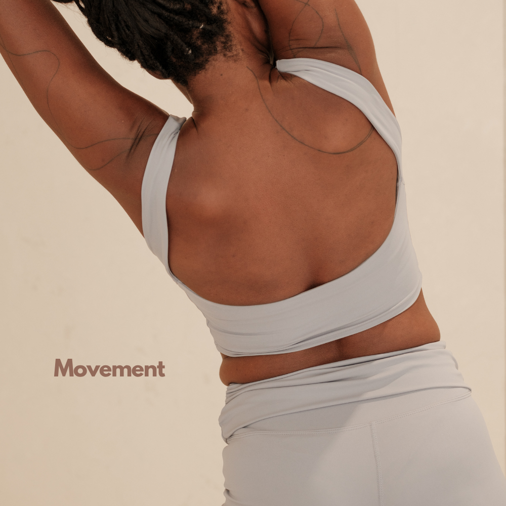 A person with dark skin and dreadlocks is stretching, wearing a white sports top and matching leggings, with the word 'Movement' written on the left side.