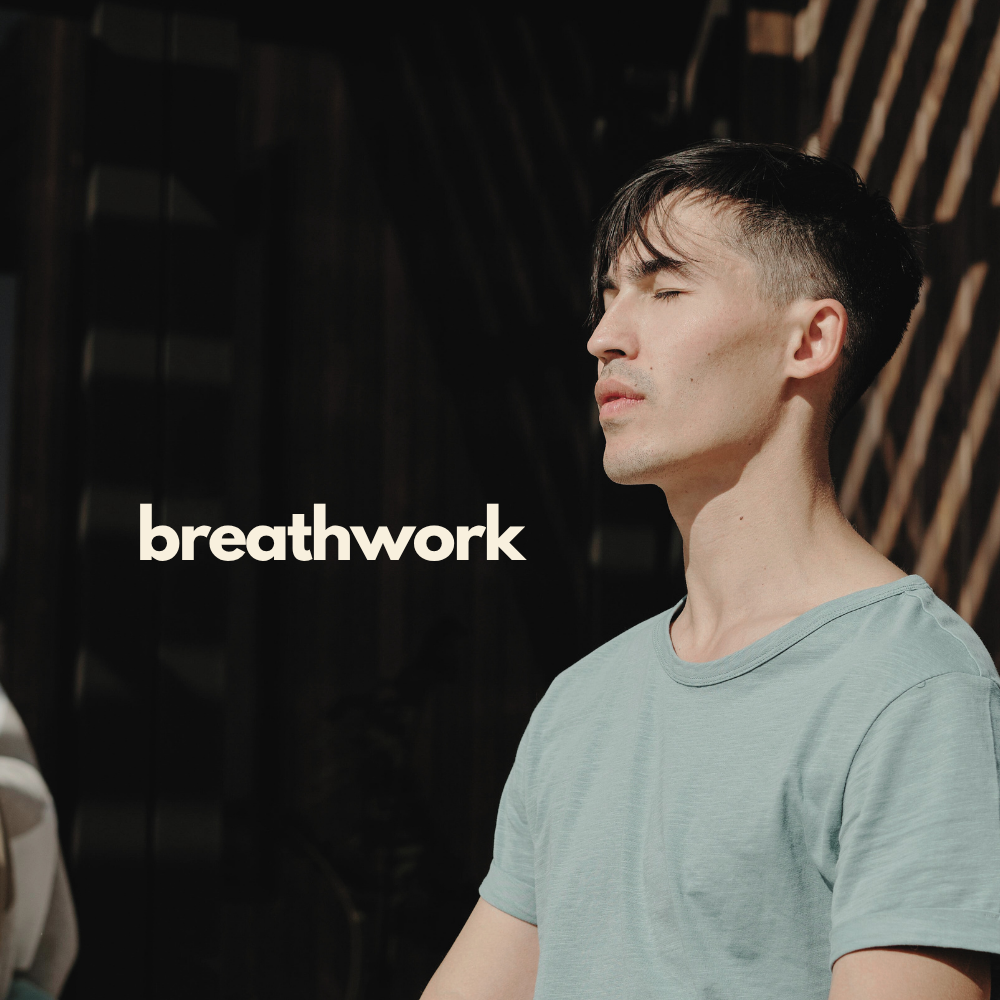 A man practicing breathing exercises outdoors with his eyes closed, sunlight on his face, wearing a light blue t-shirt, with the word 'breathwork' overlayed.
