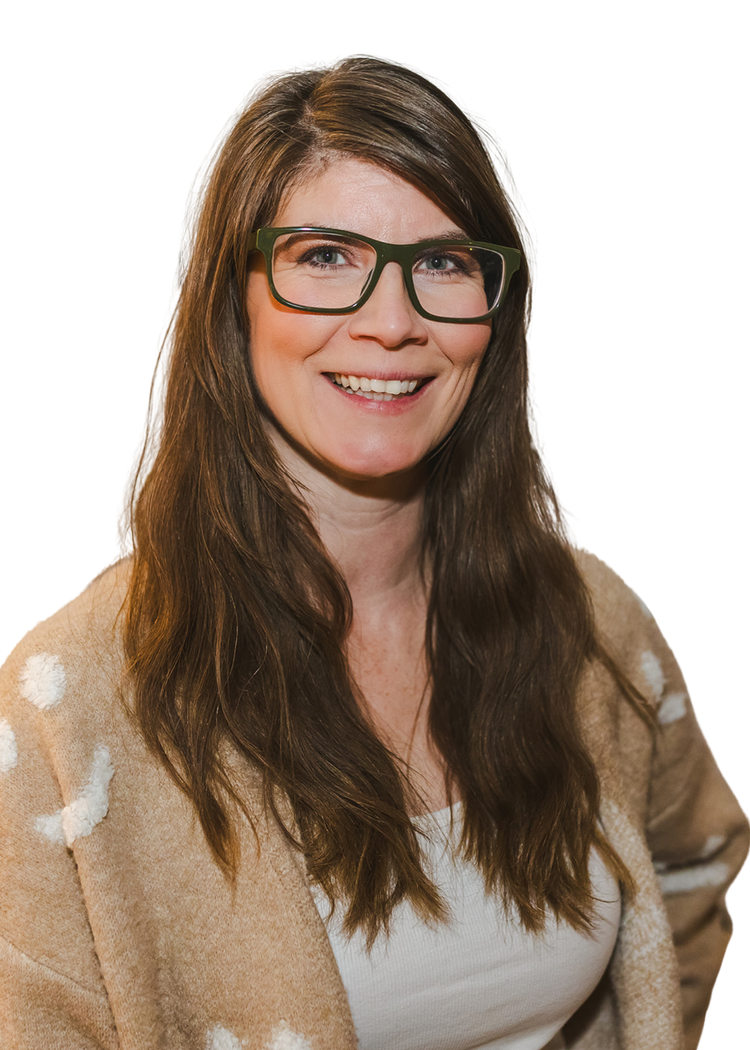 Smiling woman with brown hair, black glasses, wearing a beige coat with white polka dots, and a white top.