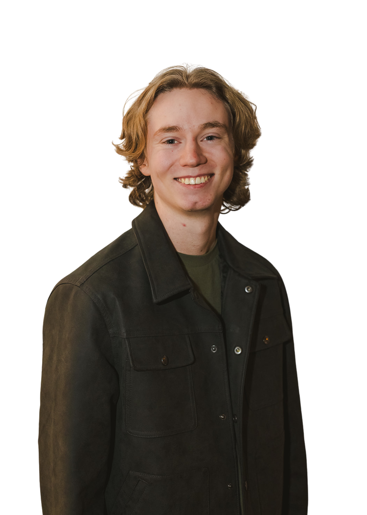 A young man with fair skin, wavy, shoulder-length blond hair, smiling, wearing a black jacket over a dark t-shirt, against a plain white background.