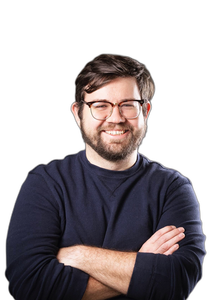 A smiling man with glasses, a beard, and short brown hair, wearing a navy blue sweater, crossing his arms against a white background.