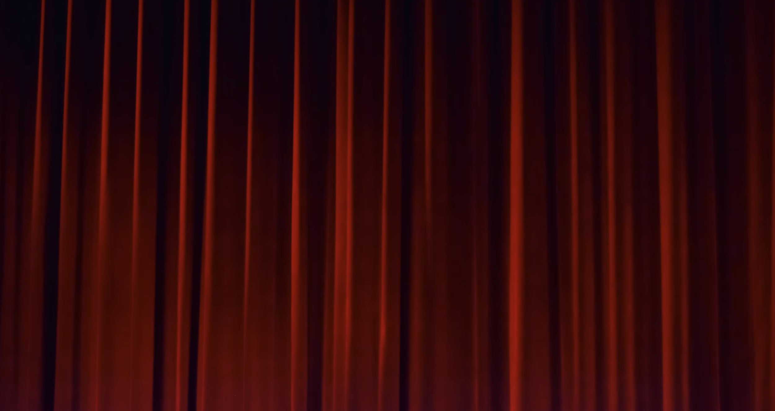 A closed red curtain with vertical pleats.