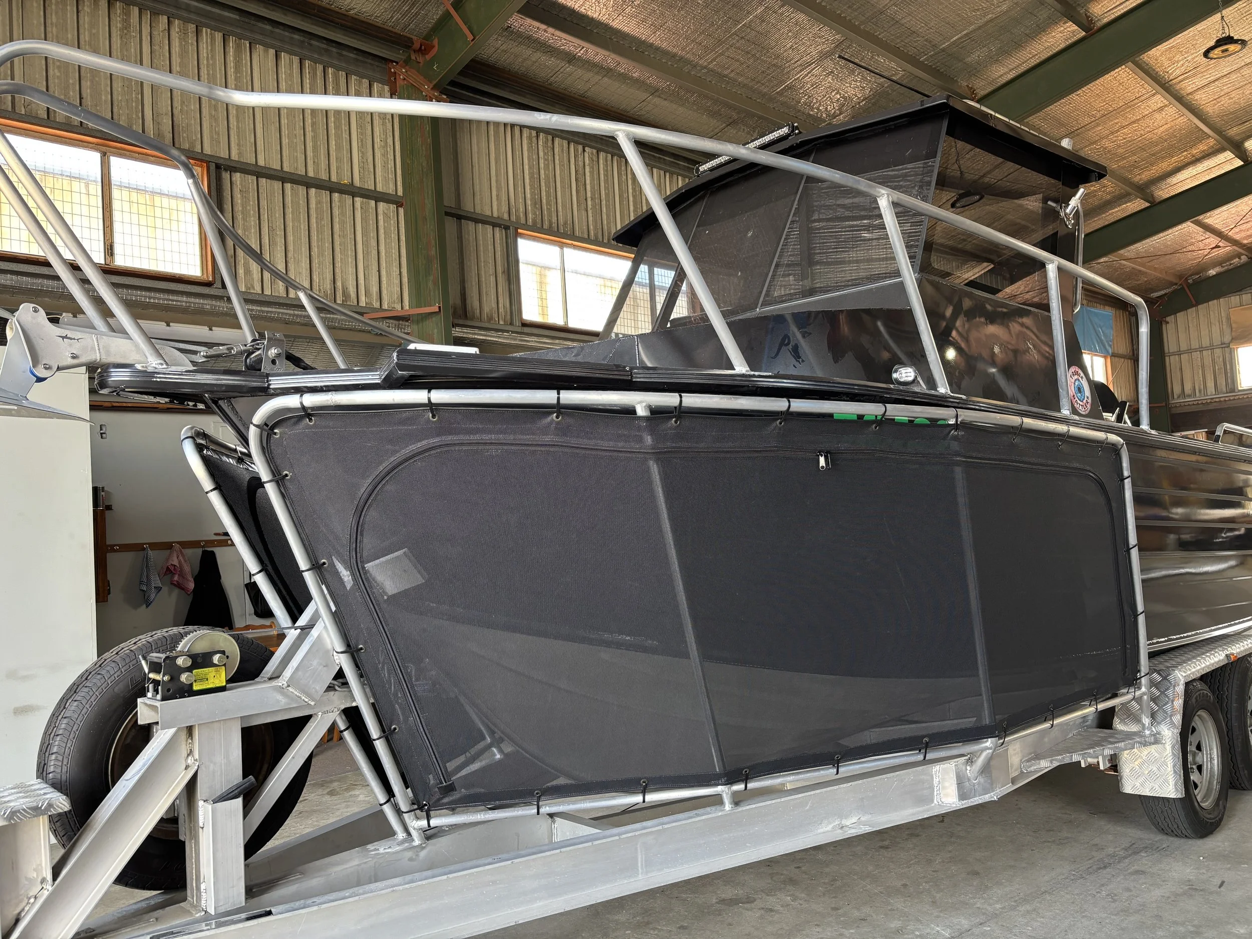 A black and silver off-road vehicle with a sturdy metal frame and large tires, stored inside a barn or warehouse with wood panel walls and windows.