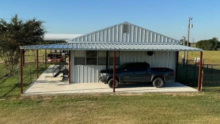This 1,000 sq. ft. porch addition features steel columns, a concrete slab, and a seamless tie-in to the existing metal building, providing expanded covered parking and outdoor functionality.
