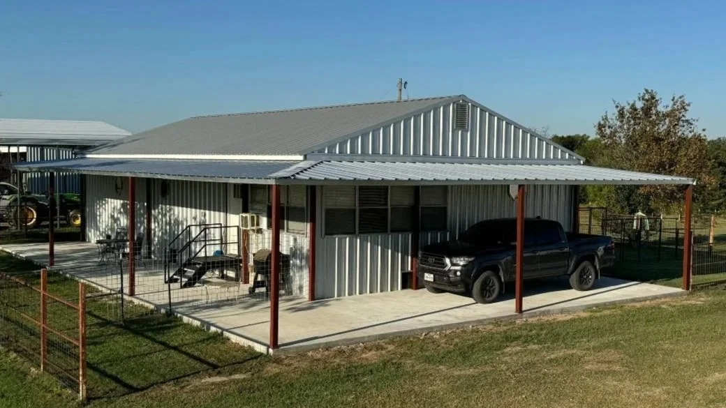 This 1,000 sq. ft. porch addition features steel columns, a concrete slab, and a seamless tie-in to the existing metal building, providing expanded covered parking and outdoor functionality.