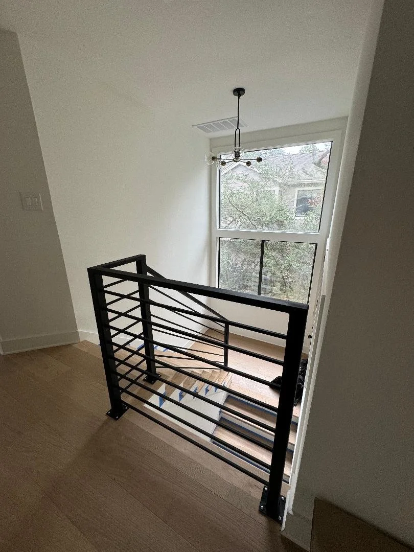 This modern stair railing features clean lines and a sleek profile that complements the open staircase. The simple design adds safety without taking away from the space.