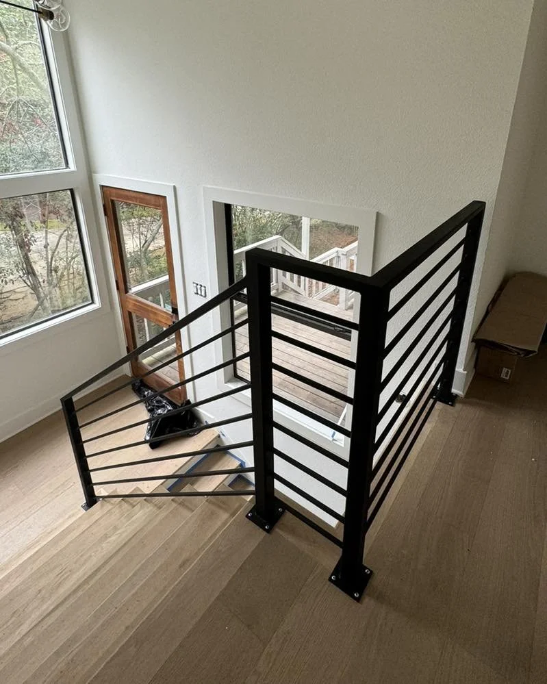 This modern stair railing features clean lines and a sleek profile that complements the open staircase. The simple design adds safety without taking away from the space.