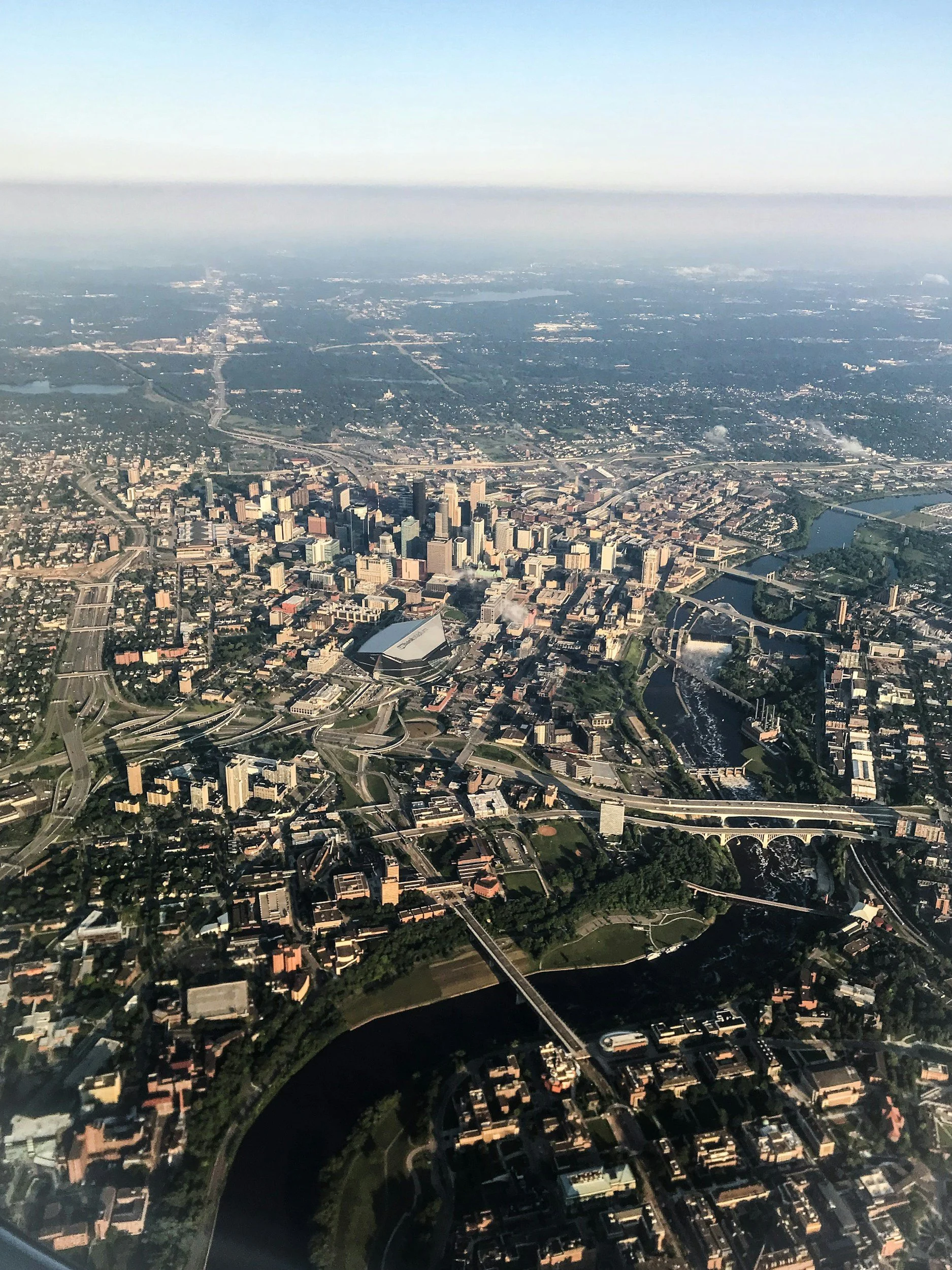 An aerial view of a cityscape with numerous buildings, roads, bridges, and rivers, taken from high altitude.