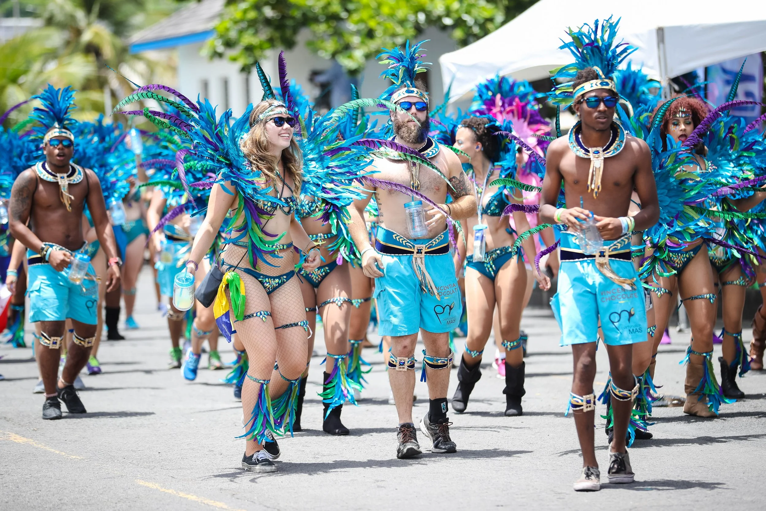 Group of people in colorful carnival costumes walking on street during parade.