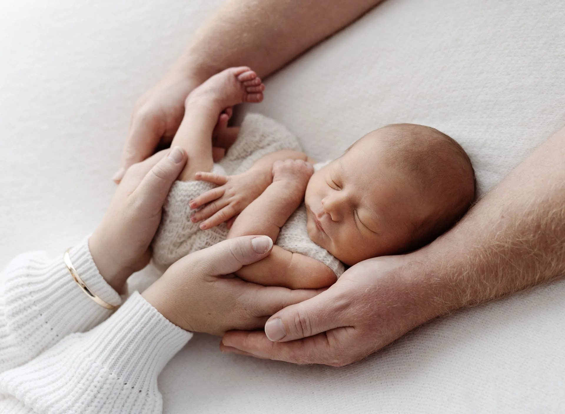 Parents gently holding their newborn baby during photography session in Canterbury NZ