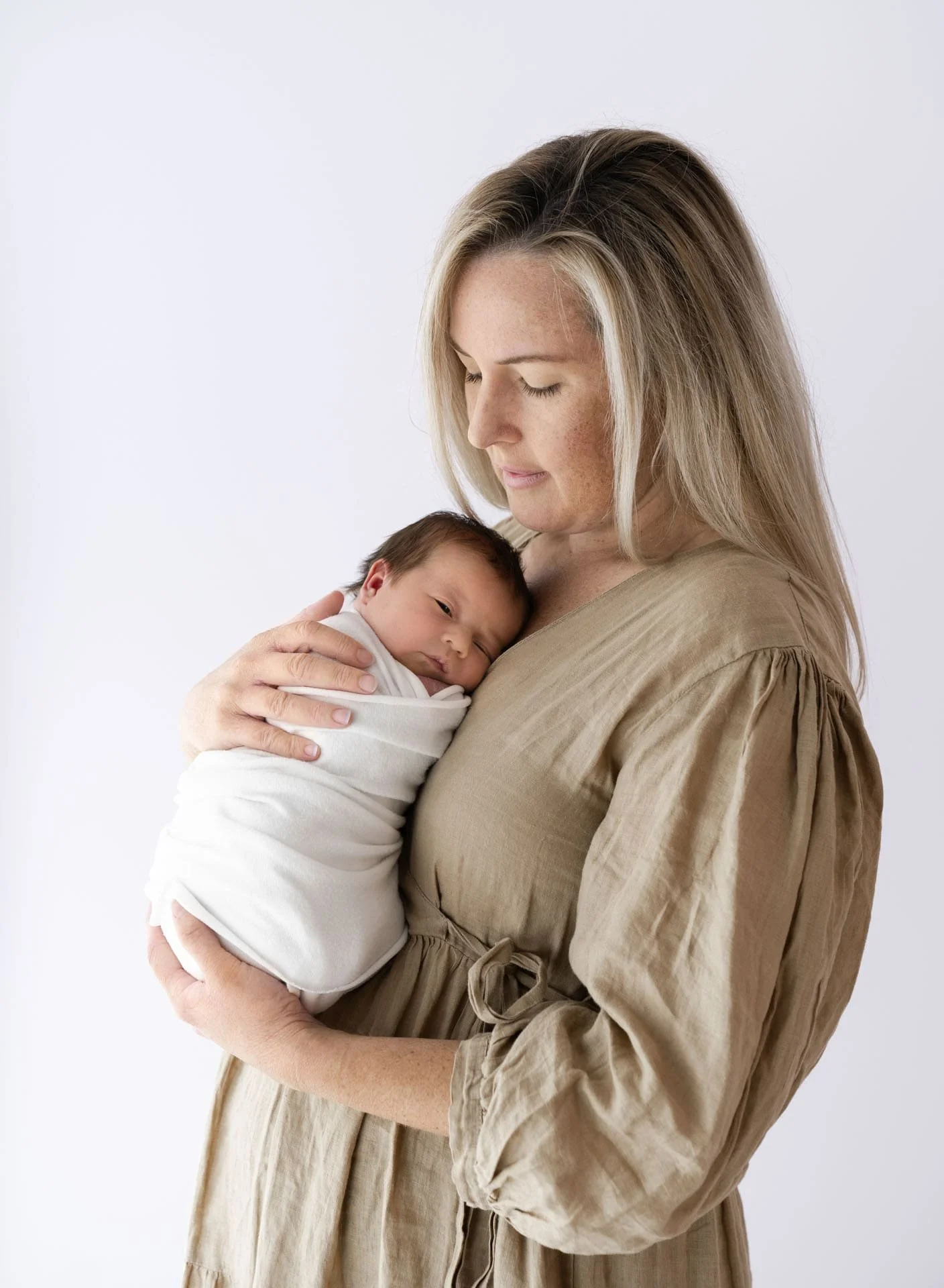 Mother cuddling newborn baby in Bishopdale studio during newborn photography session