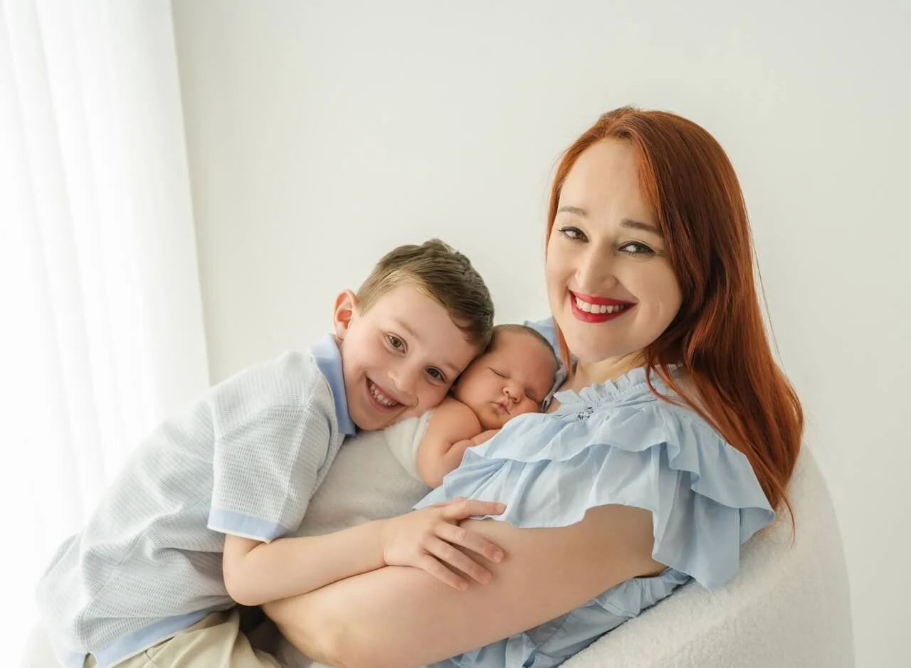 Parent and sibling cuddling newborn baby in Bishopdale studio