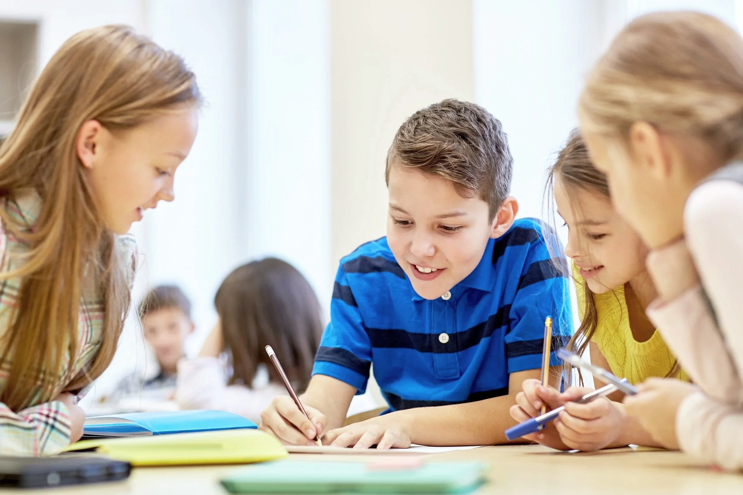 Group of children studying and collaborating at a table in a classroom.
