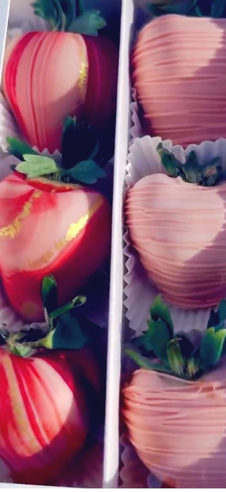 Colorful strawberries on the left and peach-colored chocolates on the right, each decorated and placed in individual paper cups.