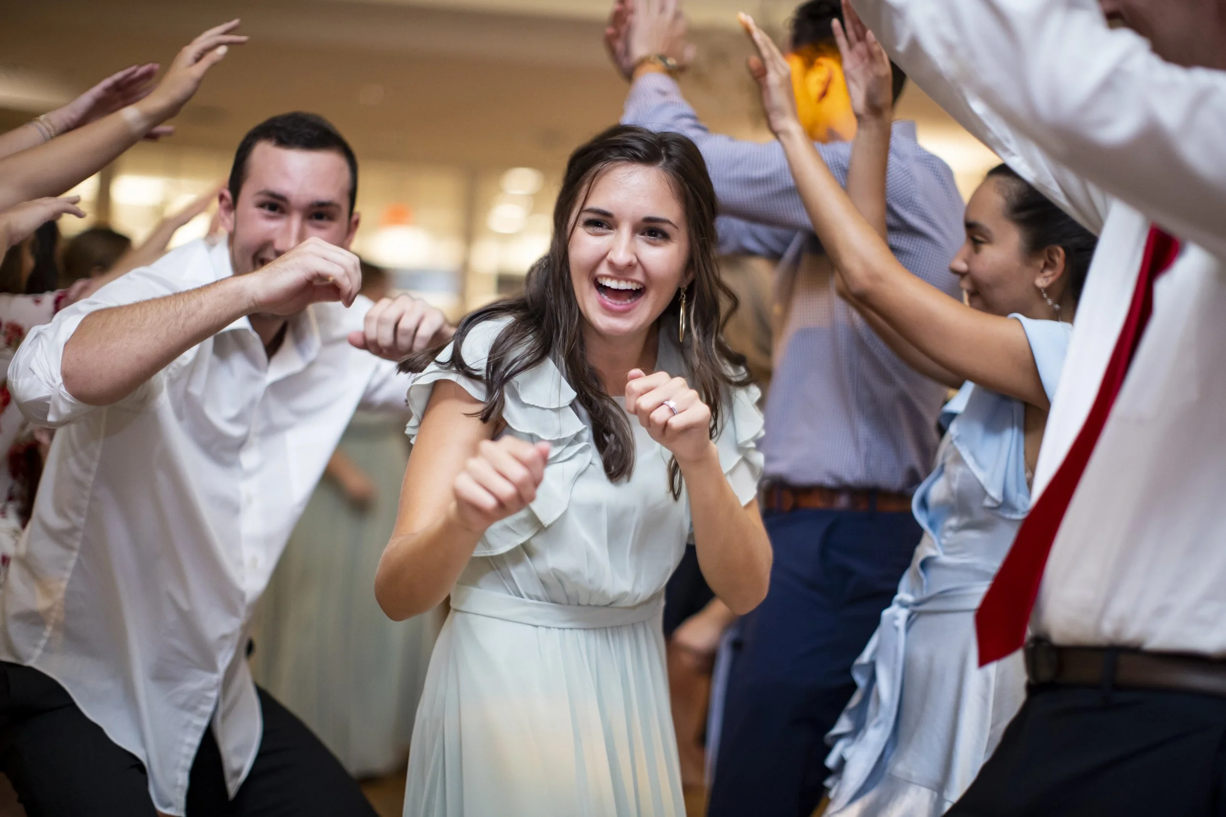 Group of people dancing and celebrating at a lively indoor event, smiling and enjoying themselves.