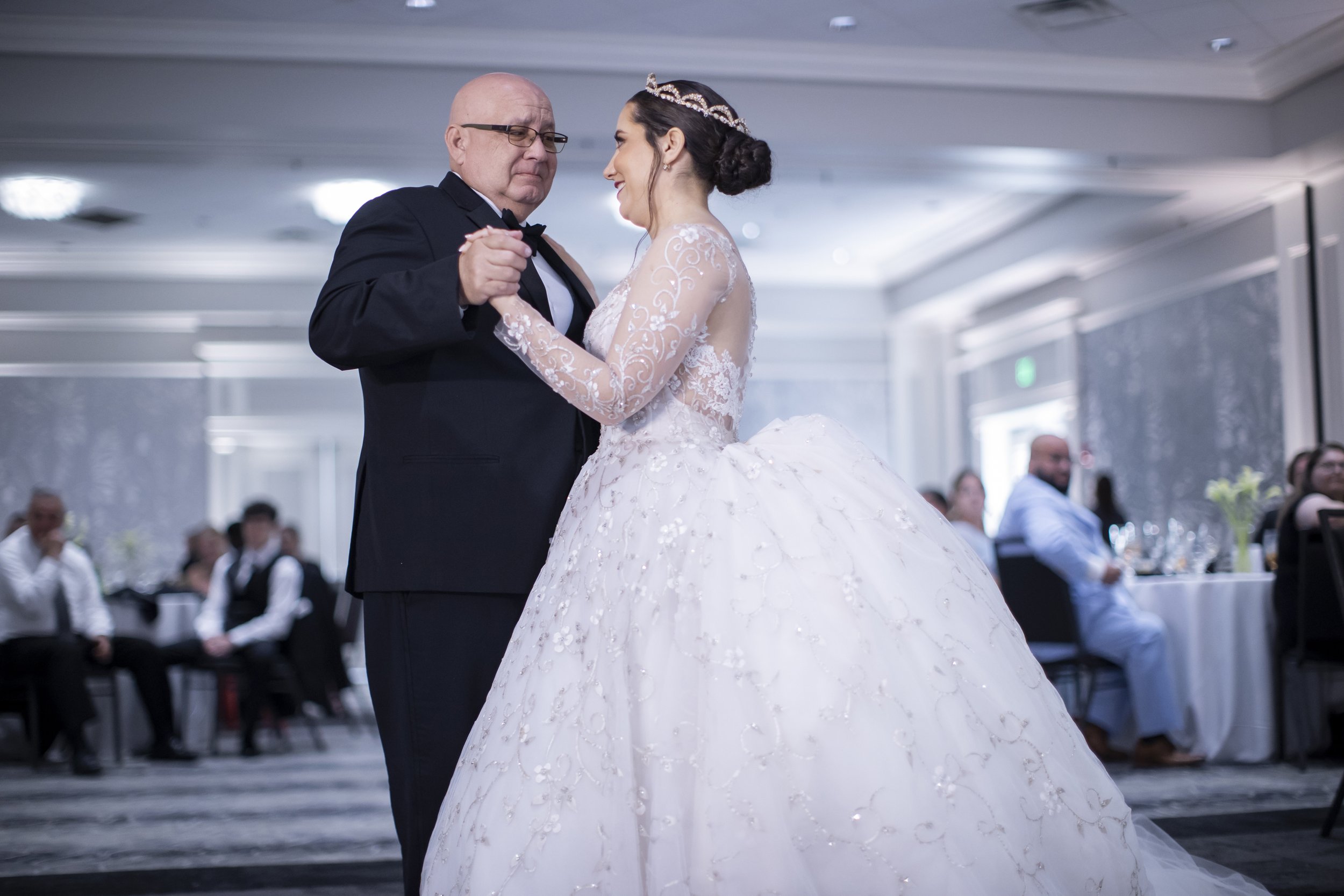 A bride and an older man dancing at a wedding reception.