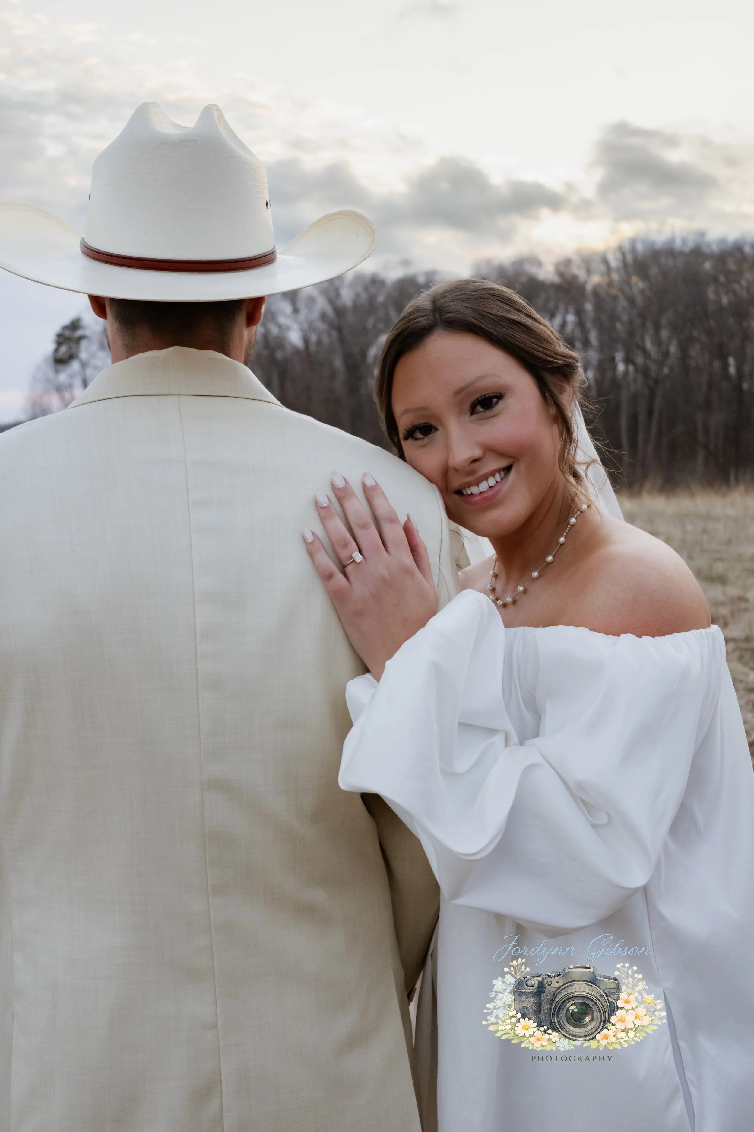 Couple standing in a field with a veil in a white dress. Elopement Photography Sophia NC