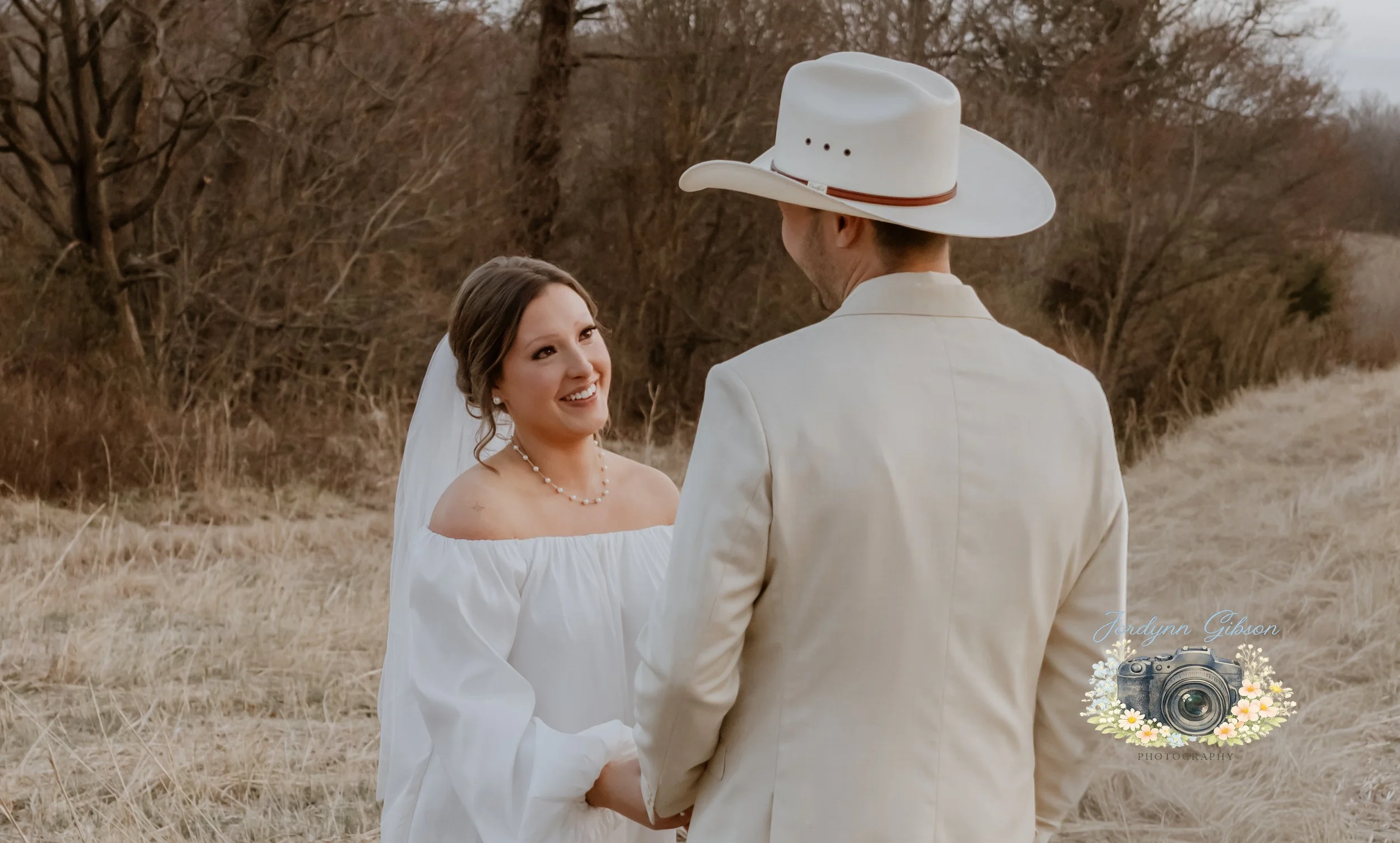 Couple standing in a field with a veil in a white dress. Elopement Photography Sophia NC