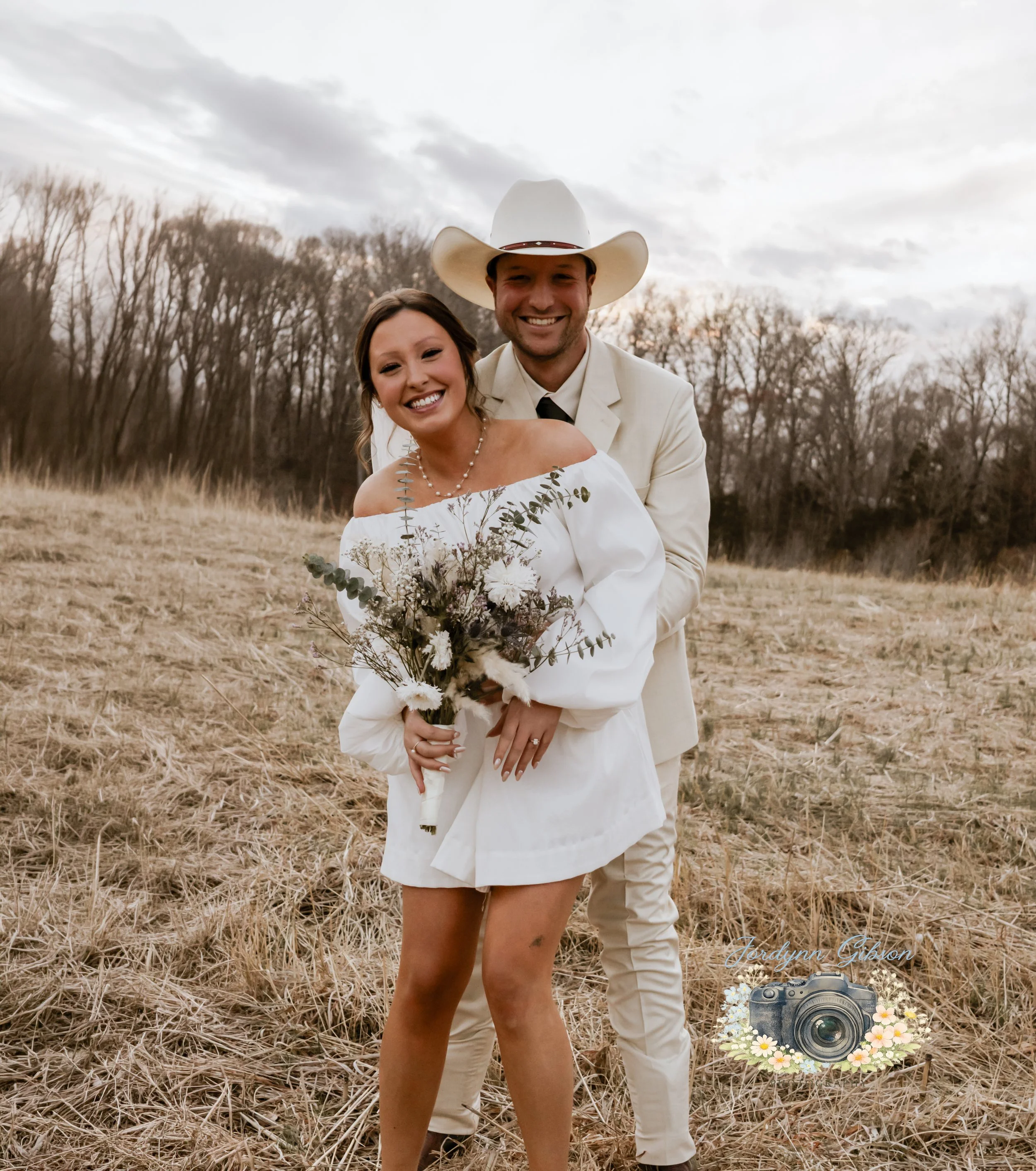 Couple standing in a field with a veil in a white dress. Elopement Photography Sophia NC