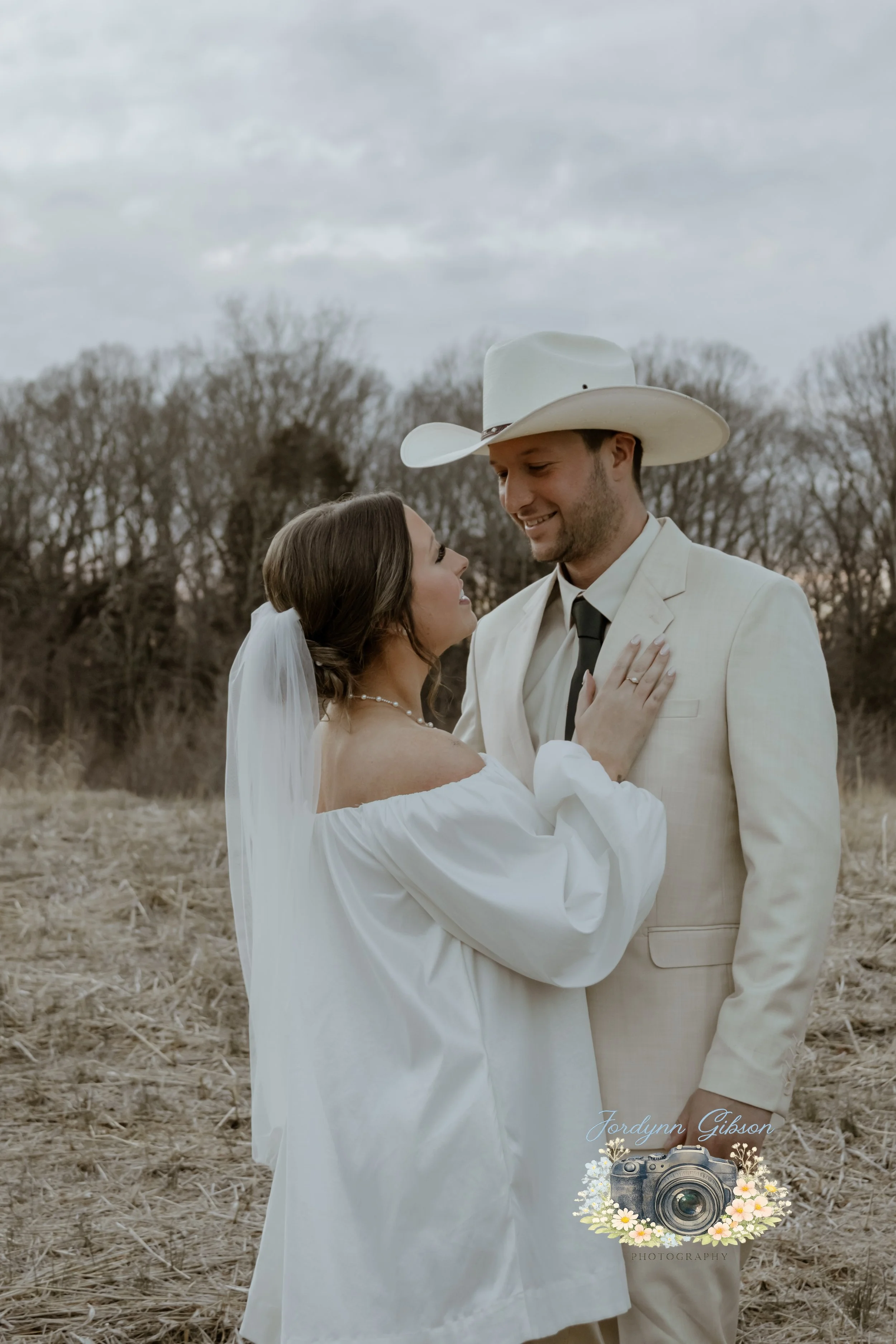 Couple standing in a field with a veil in a white dress. Elopement Photography Sophia NC
