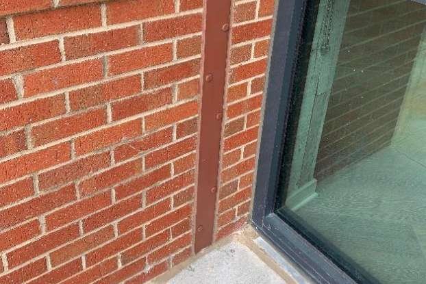 Flood barrier wall interface detail showing embedded custom mounting plate frame at masonry opening.