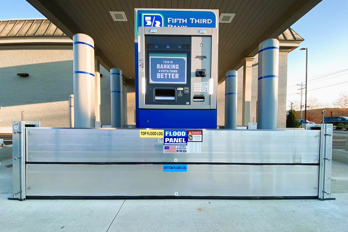 Deployable flood barrier system installed at vehicle access point to protect commercial bank infrastructure from coastal flooding.