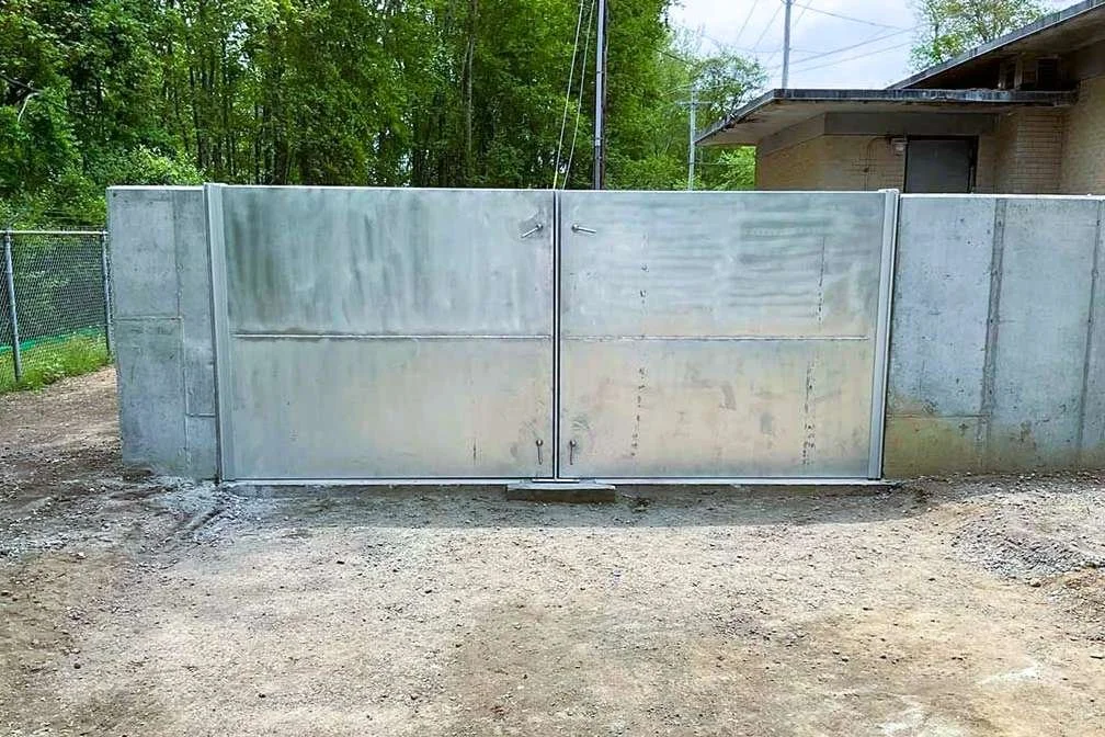 Heavy-duty galvanized flood gate installed at vehicle access point for perimeter flood control.