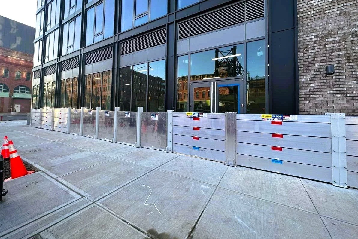 Deployable aluminum flood barrier system installed at commercial building entrance to protect against storm surge.