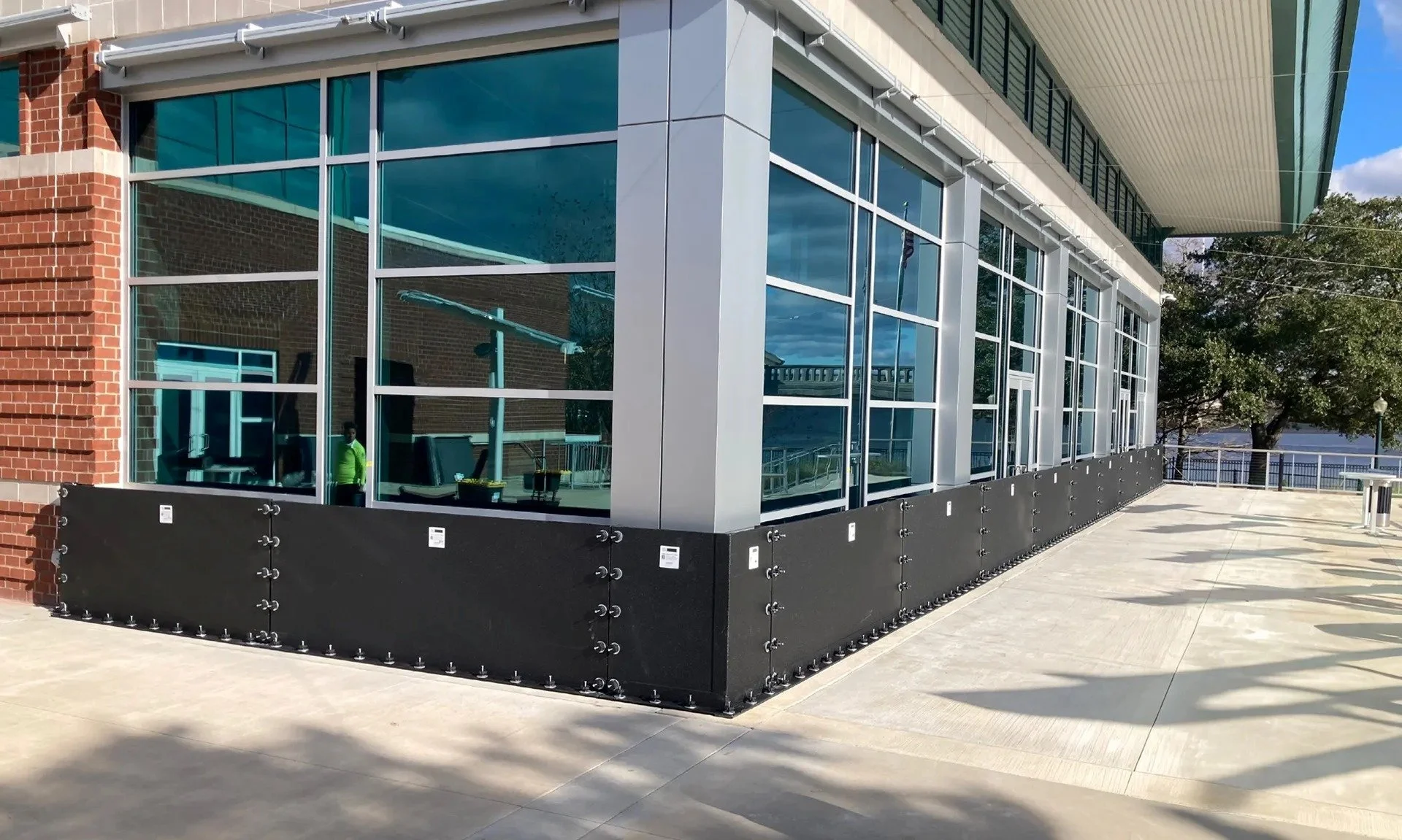 deployable composite flood barrier system protecting storefront entrances at a commercial retail property.
