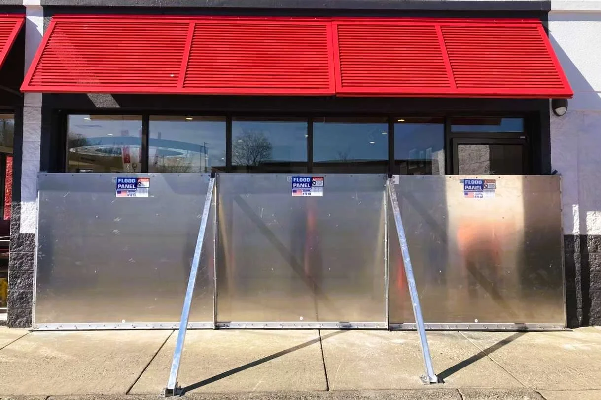 Removable flood shield panel system installed at commercial storefront entrance for temporary flood protection.