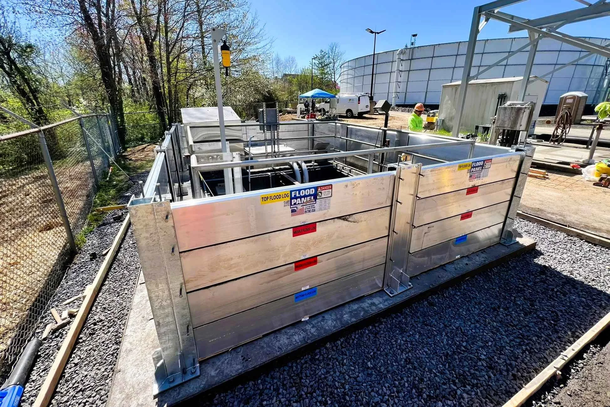 Critical infrastructure facility protected by engineered flood barrier systems to prevent operational shutdowns during storm surge