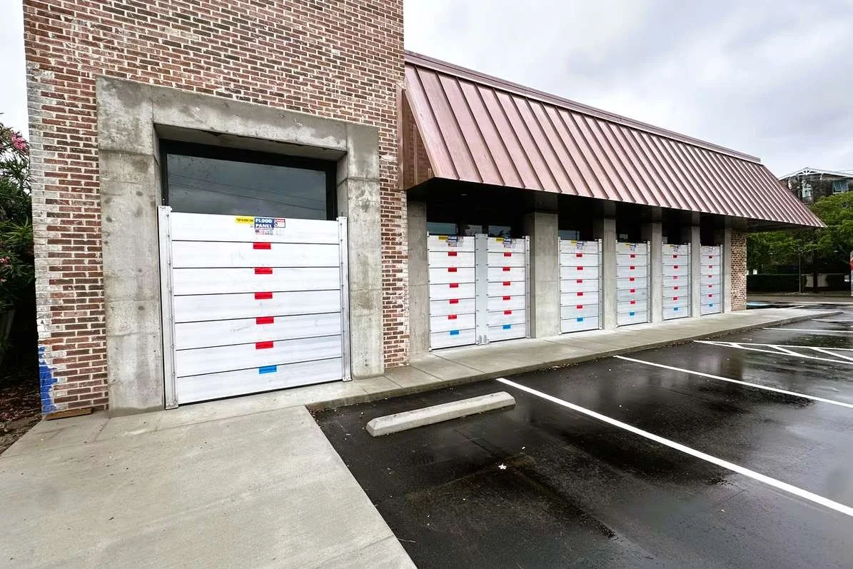 Deployable aluminum flood log barrier system installed at commercial building entrance to prevent water intrusion.
