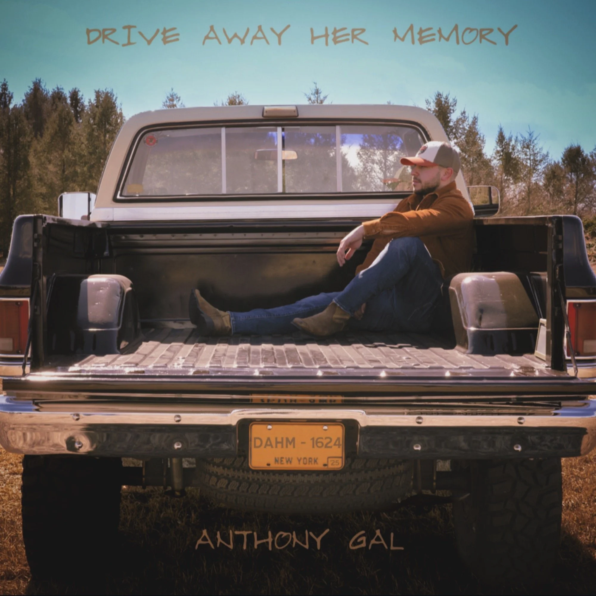 A man sitting in the back of a pickup truck's empty bed with trees in the background. Text at the top reads 'Drive Away Her Memory'. Text at the bottom reads 'Anthony Gal'.