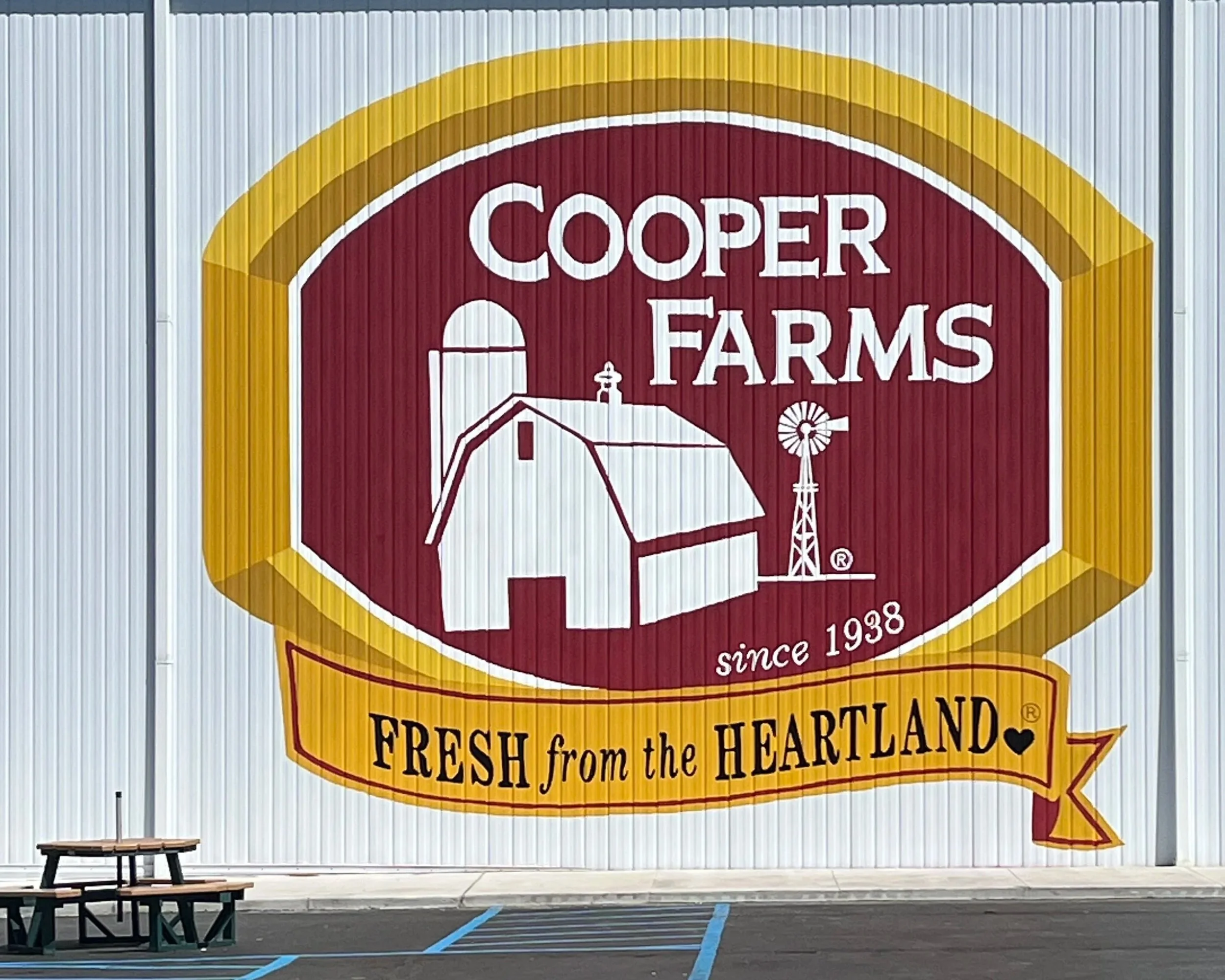 Large sign for Cooper Farms featuring a barn, silo, windmill, and the text 'since 1938.' Banner below reads 'FRESH from the HEARTLAND.'