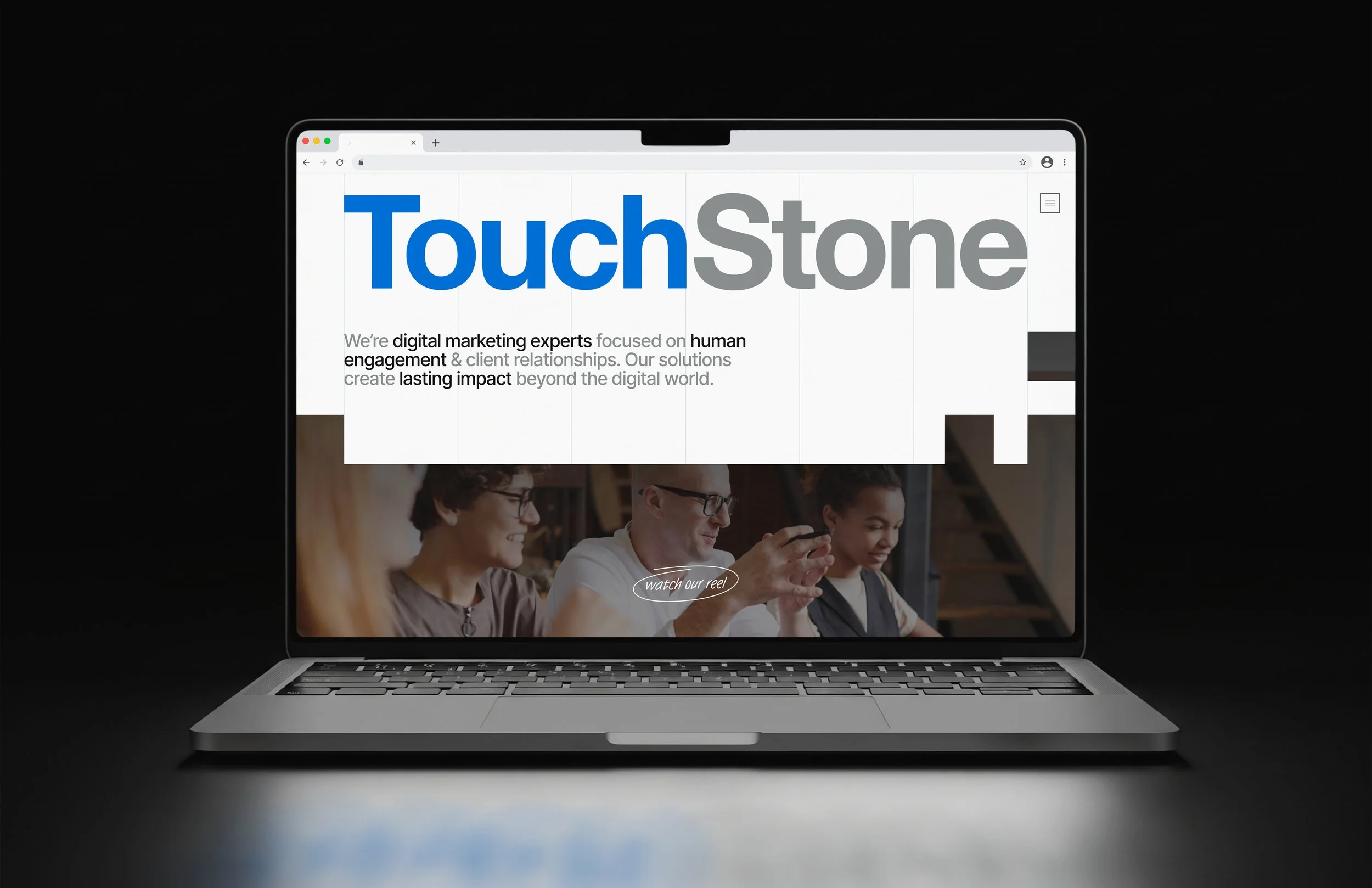 Laptop screen displaying the TouchStone digital marketing company's website with text and a photo of a group of people using tablets.