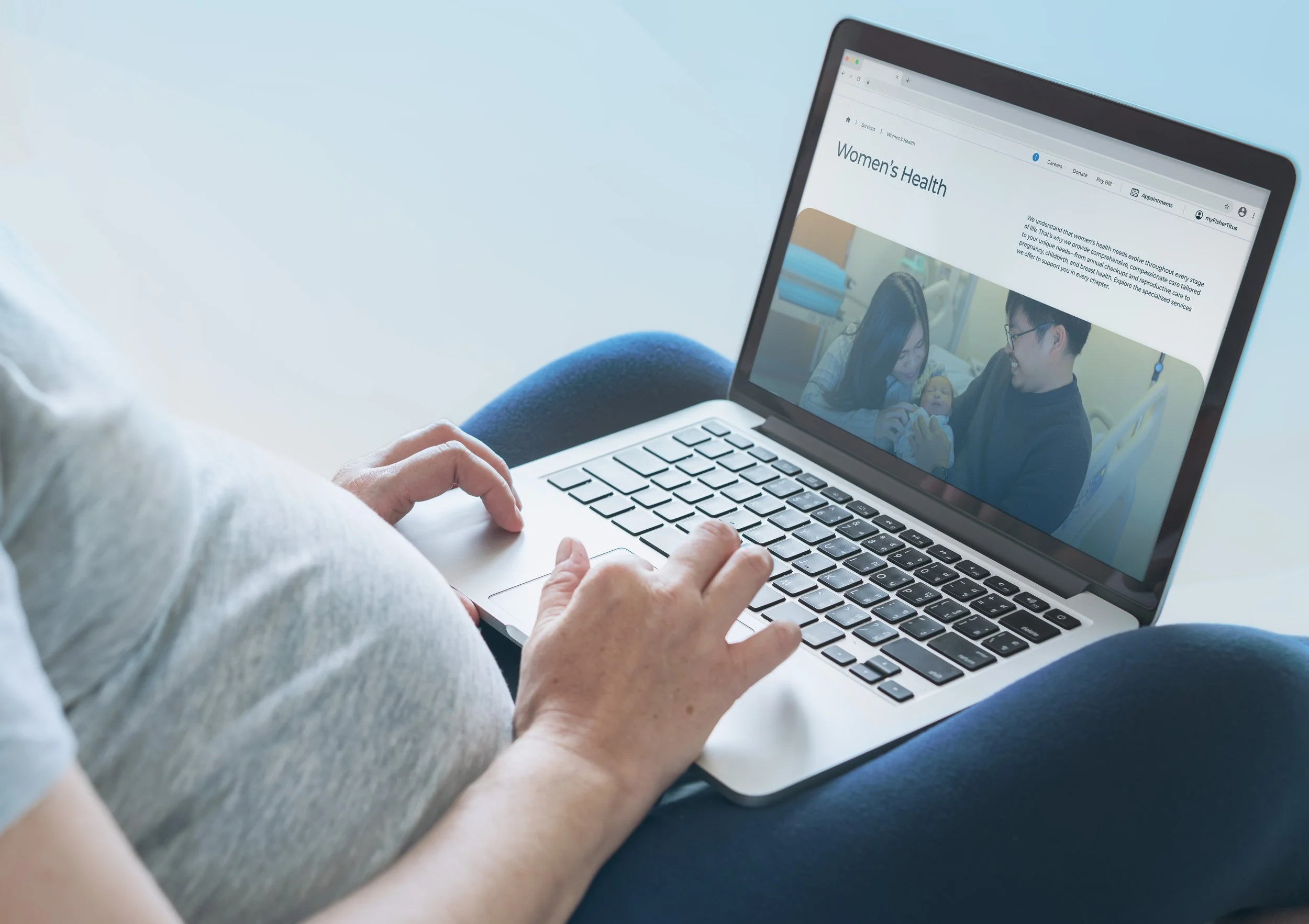 Person using a laptop displaying a website about women's health, with a photo of a woman and a man with a baby.