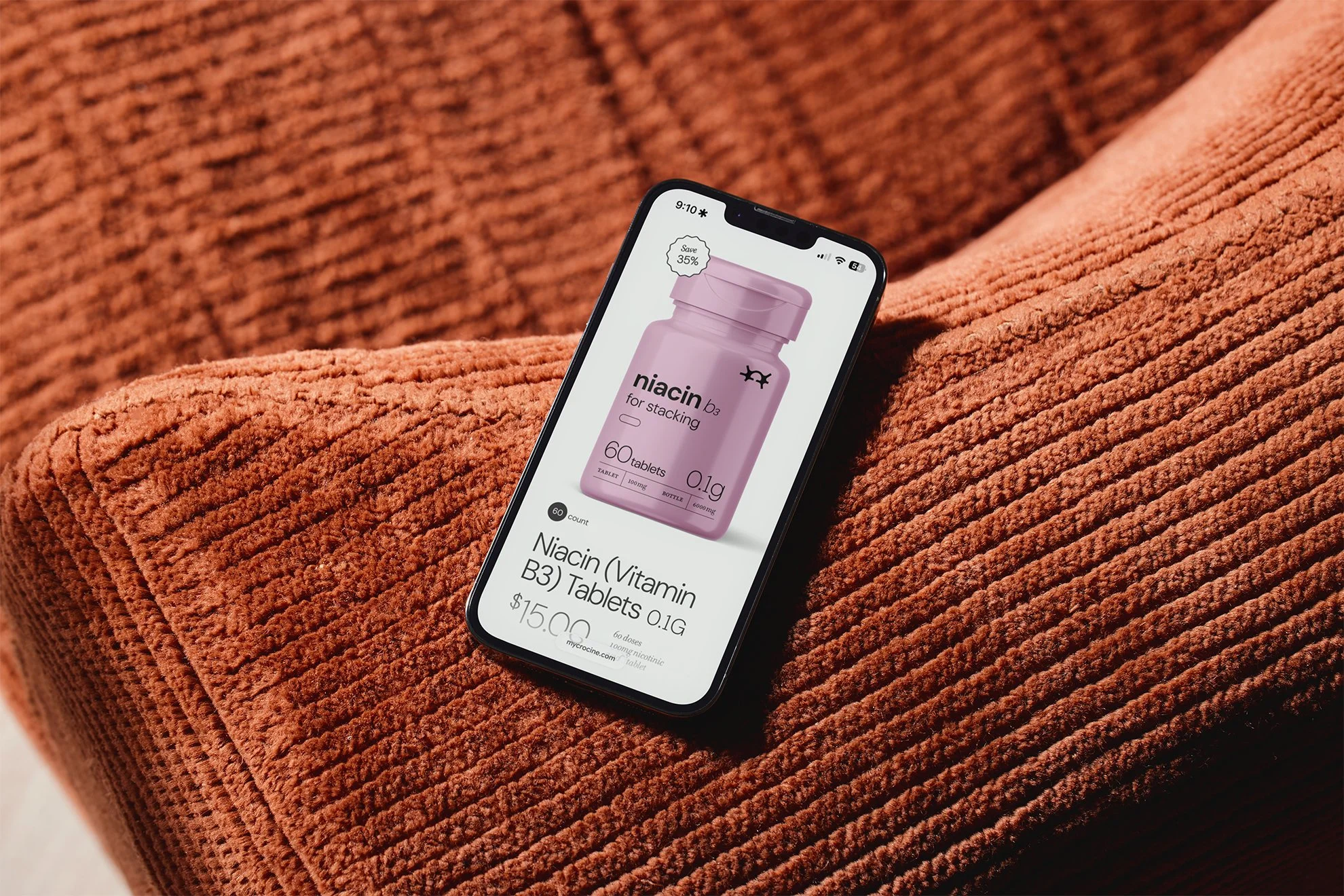 Smartphone lying on a plush, rust-colored textured blanket displaying an online shopping page for Niacin (Vitamin B3) tablets.