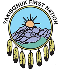 The emblem of Yakisönük First Nation featuring a sunrise over mountains, with a light blue sky, and hanging yellow feathers.