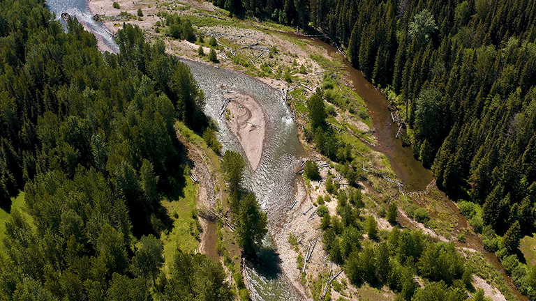 Aerial view of Corbin Road Lands, British Columbia a forested landscape with the river running through it, some areas with exposed soil and fallen trees.