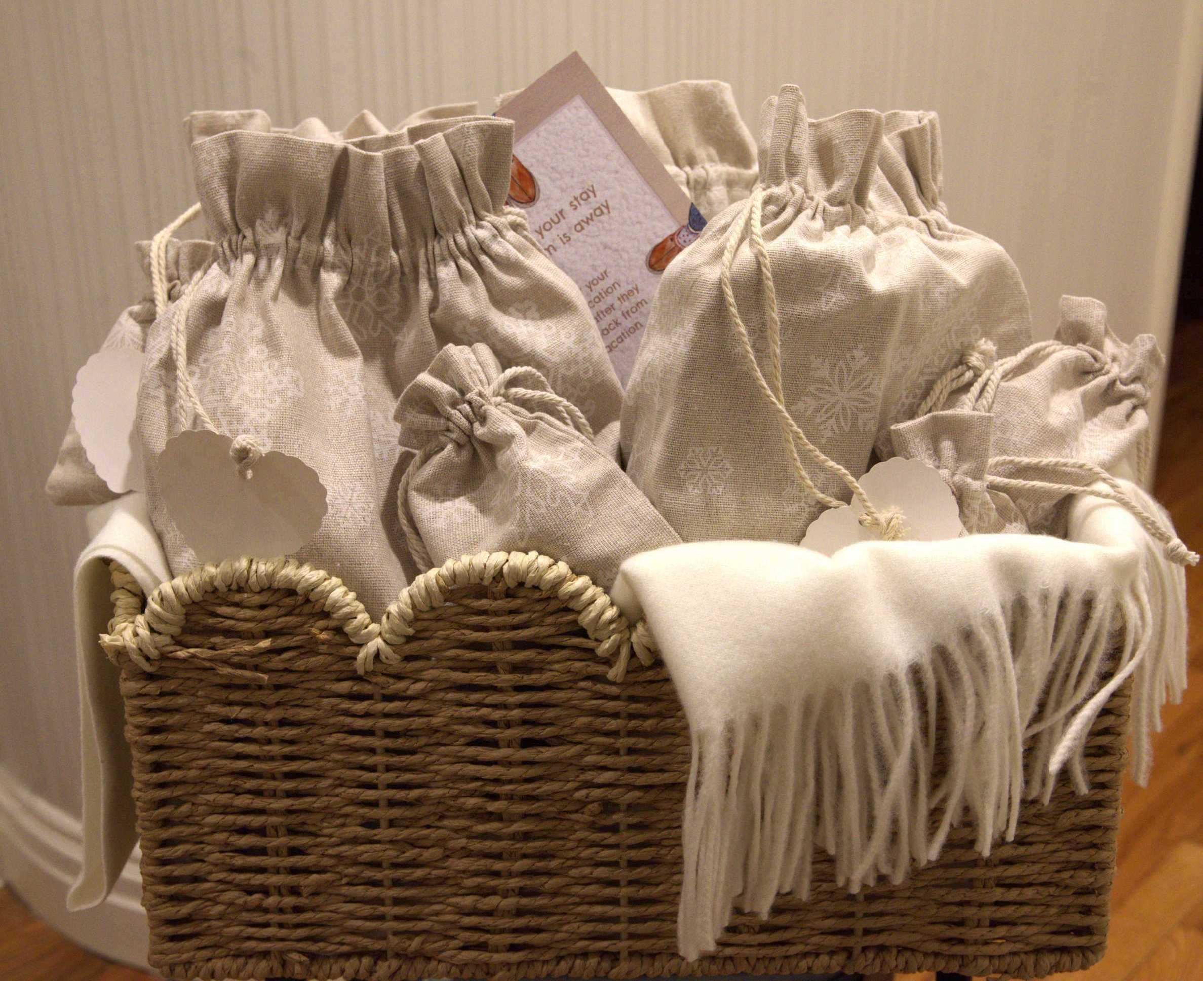 Basket filled with small beige drawstring pouches and a white fringed cloth.